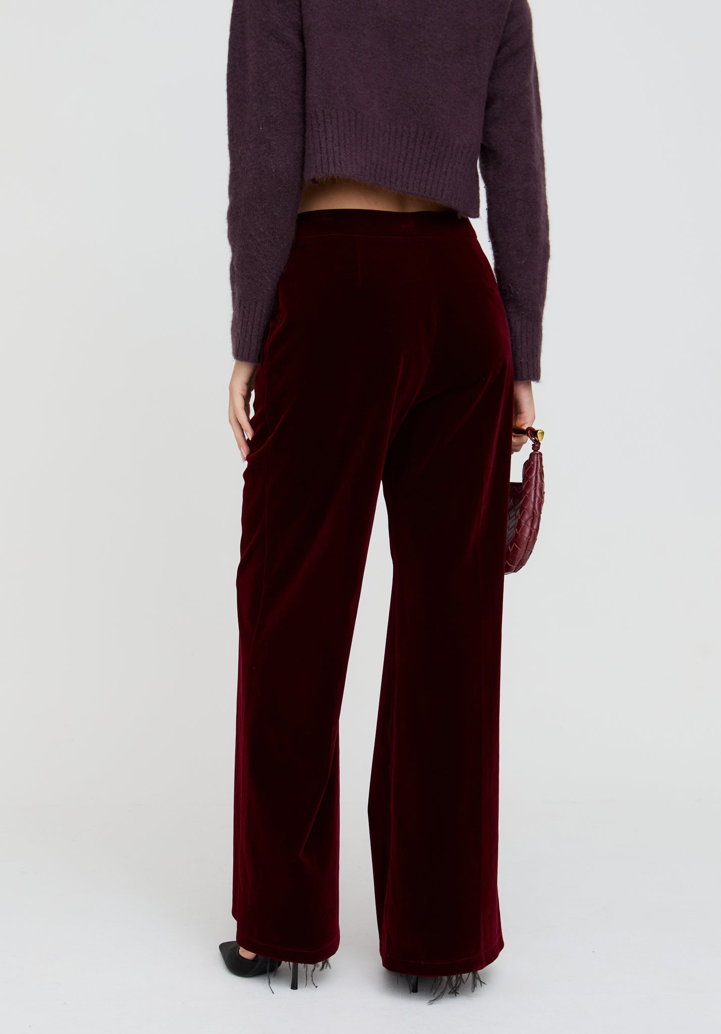 Person wearing a purple cropped sweater and burgundy wide-leg pants on a white background