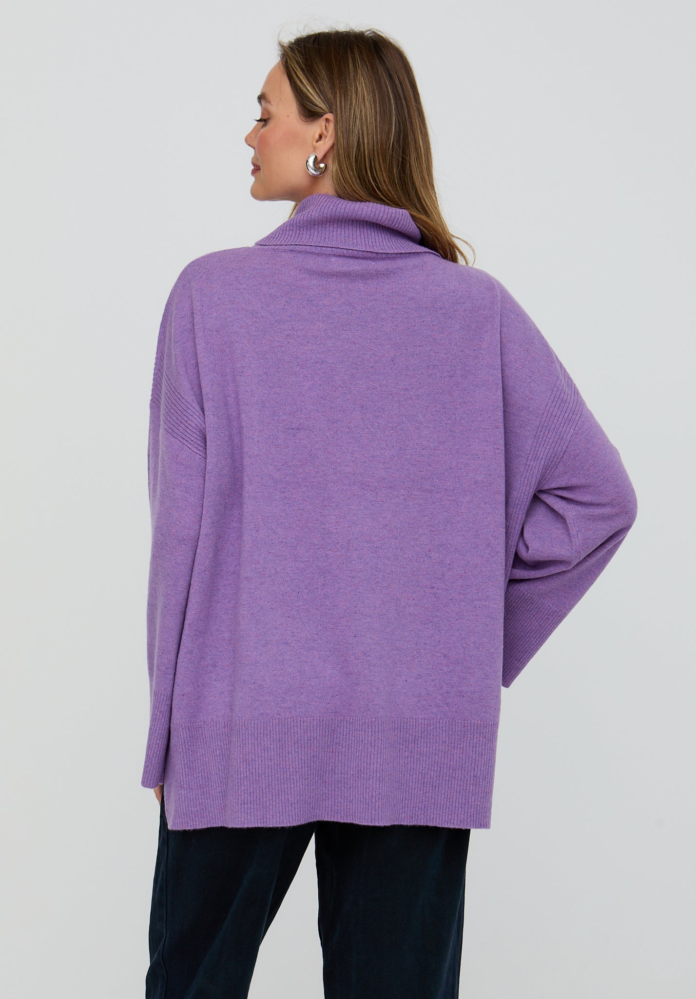Person wearing a purple sweater on a plain background