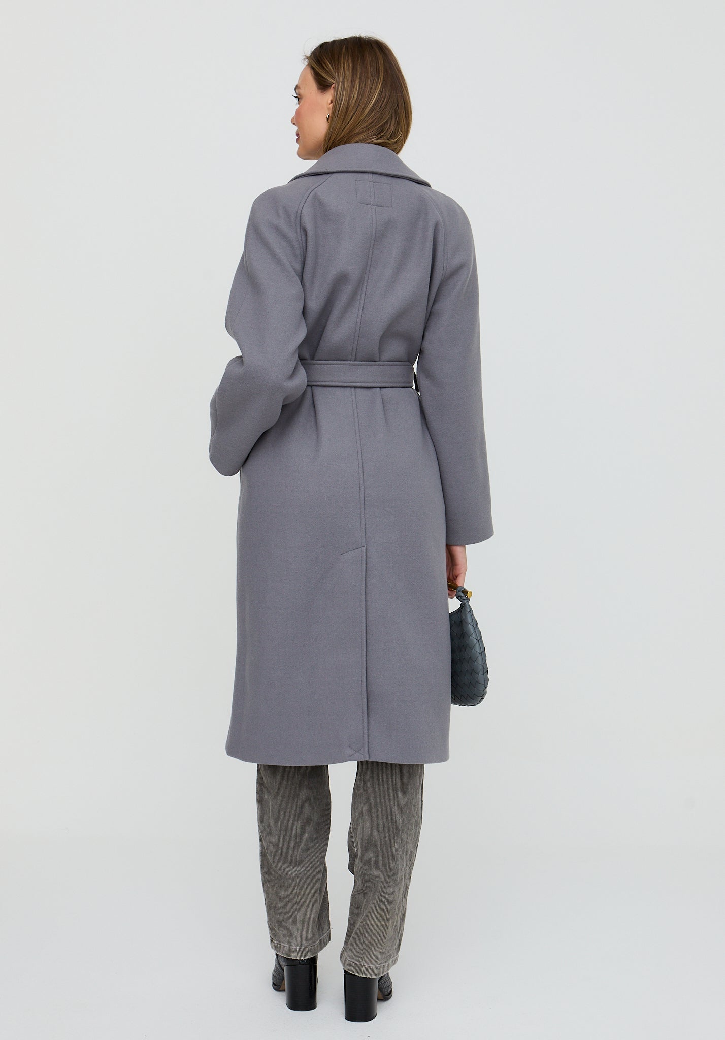 Woman wearing a gray coat and pants on a white background