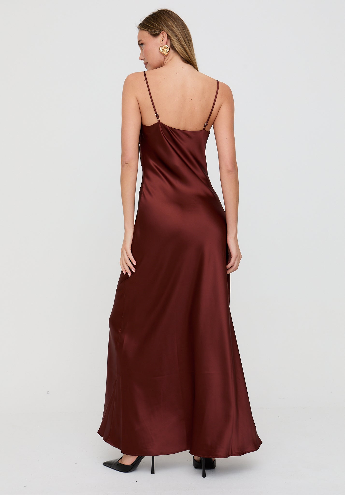 Woman wearing a burgundy satin dress on a white background