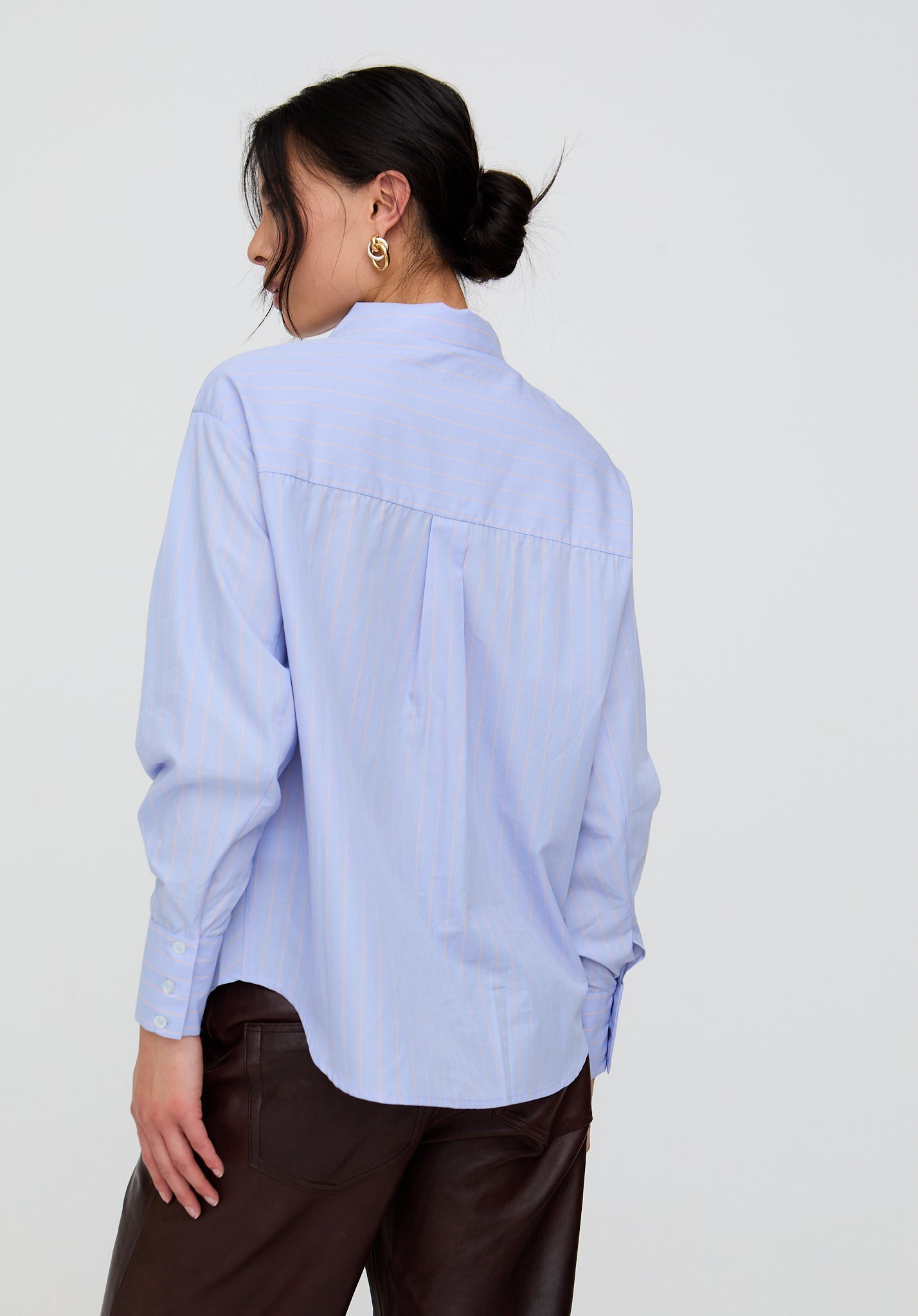 Woman wearing a light blue shirt and dark pants on a white background