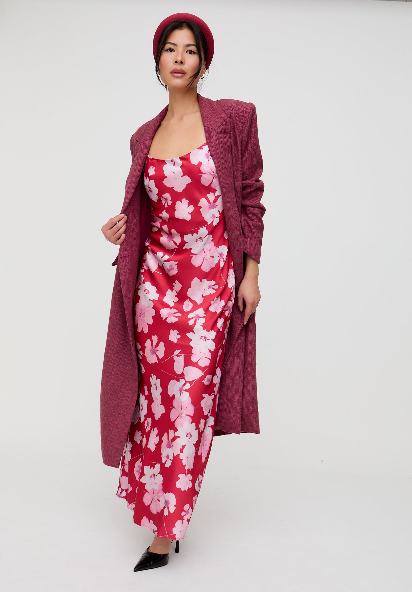 Woman wearing a pink floral dress and matching coat with a white background
