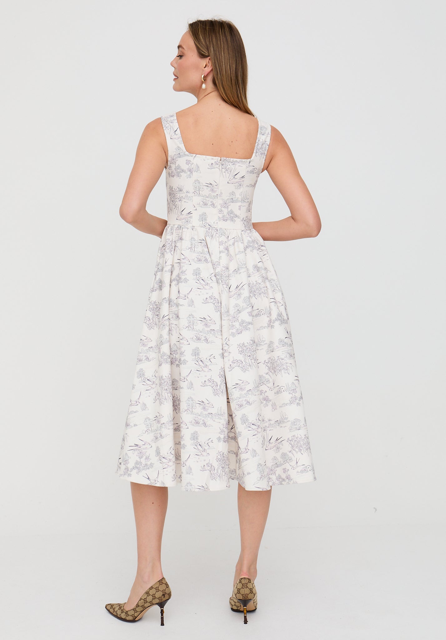 Woman wearing a white floral dress on a plain background