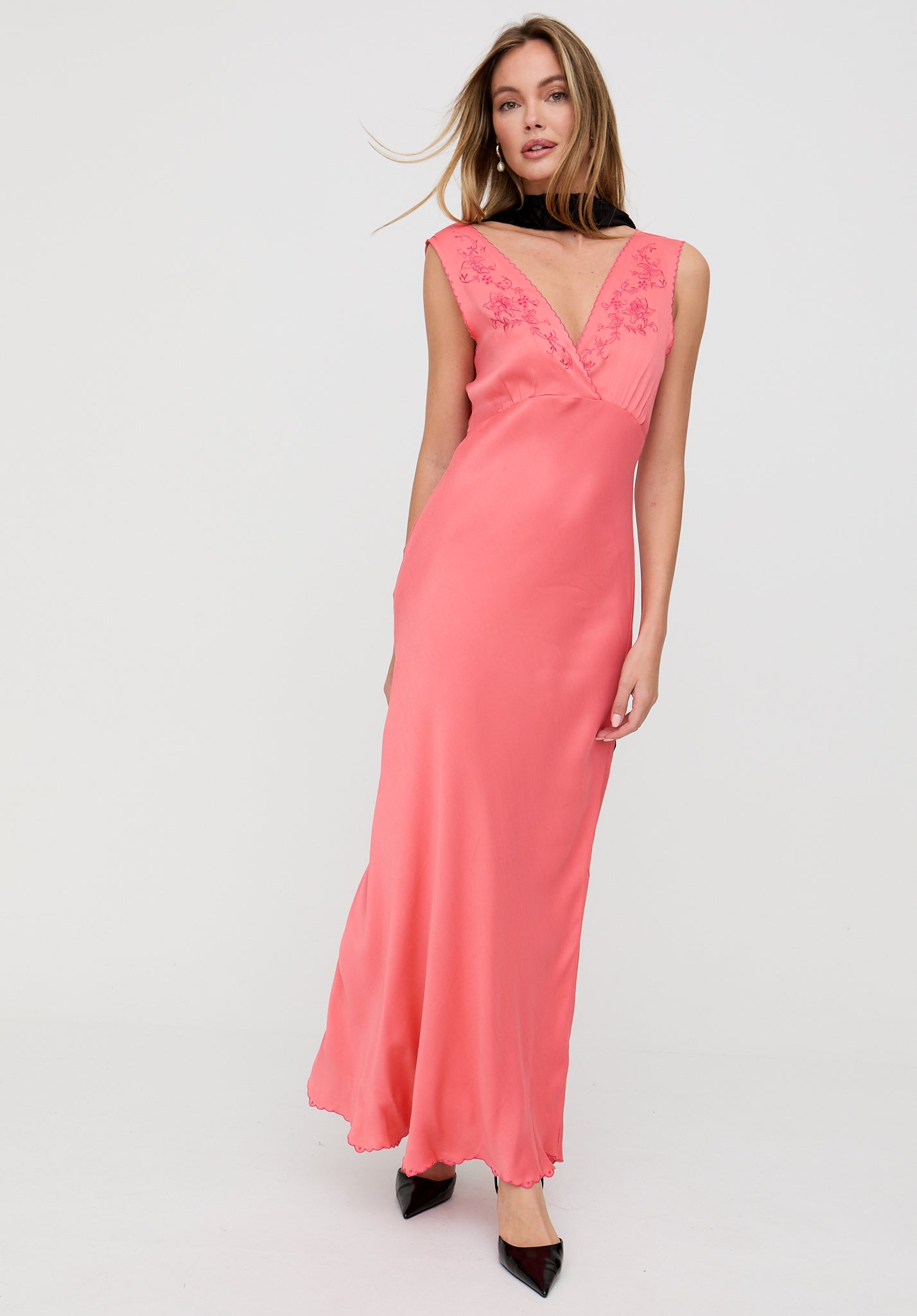 Woman wearing a pink dress with floral details on a white background