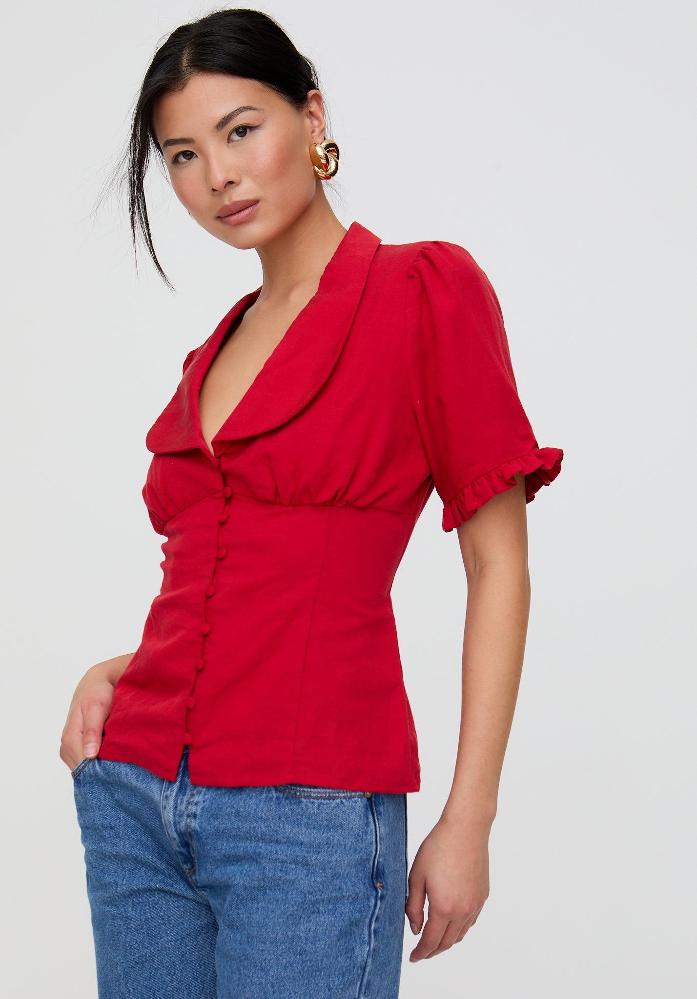 Woman wearing a red blouse with puff sleeves on a white background