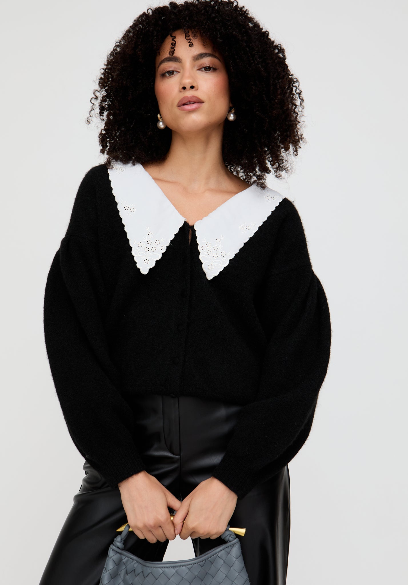 Woman wearing a black blouse with a white collar against a plain background