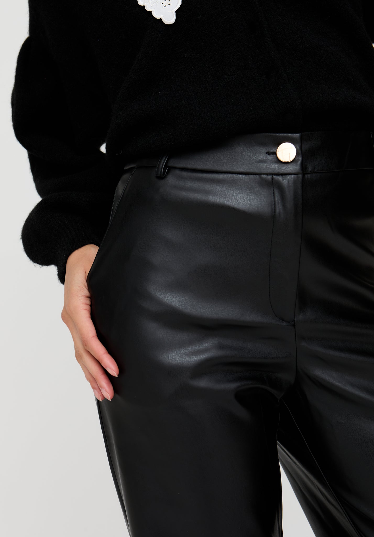 Person wearing black leather pants with a white background