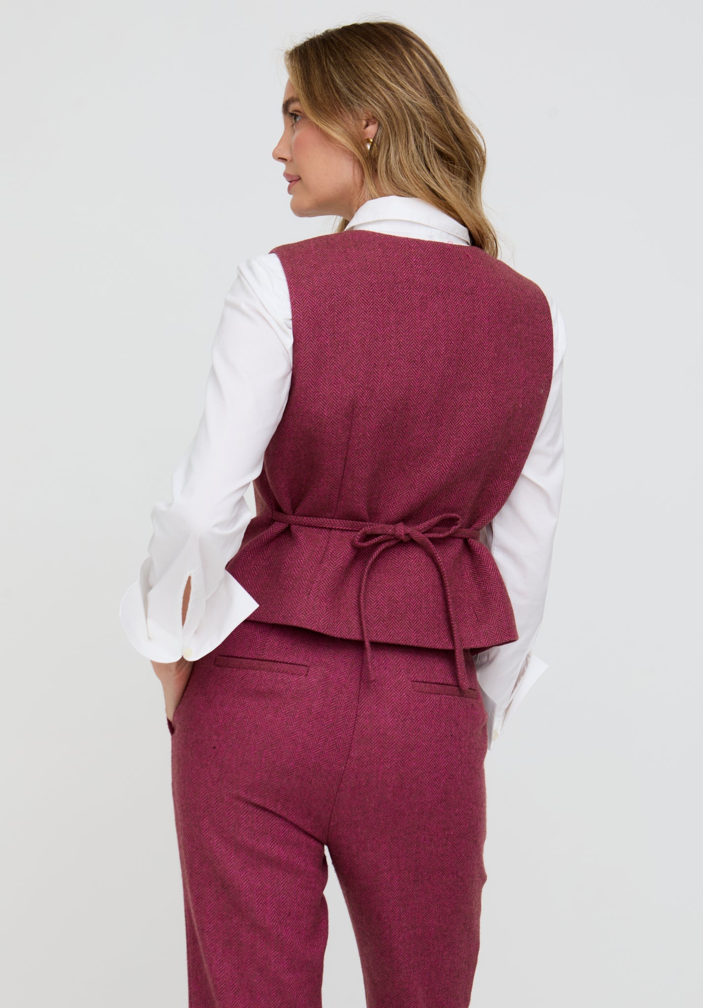 Person wearing a maroon vest and pants set on a white background