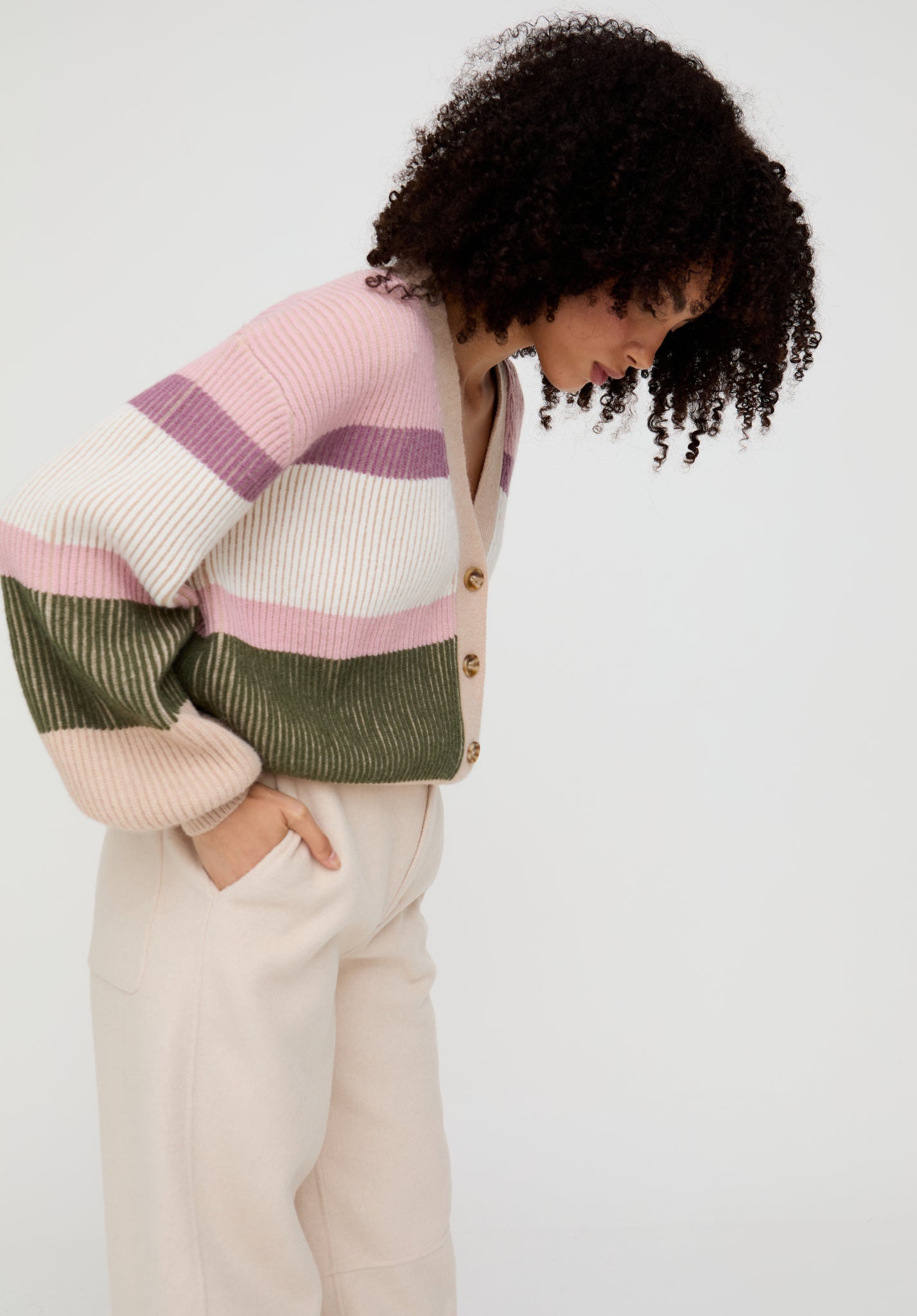 Person wearing a colorful striped sweater and beige pants on a white background