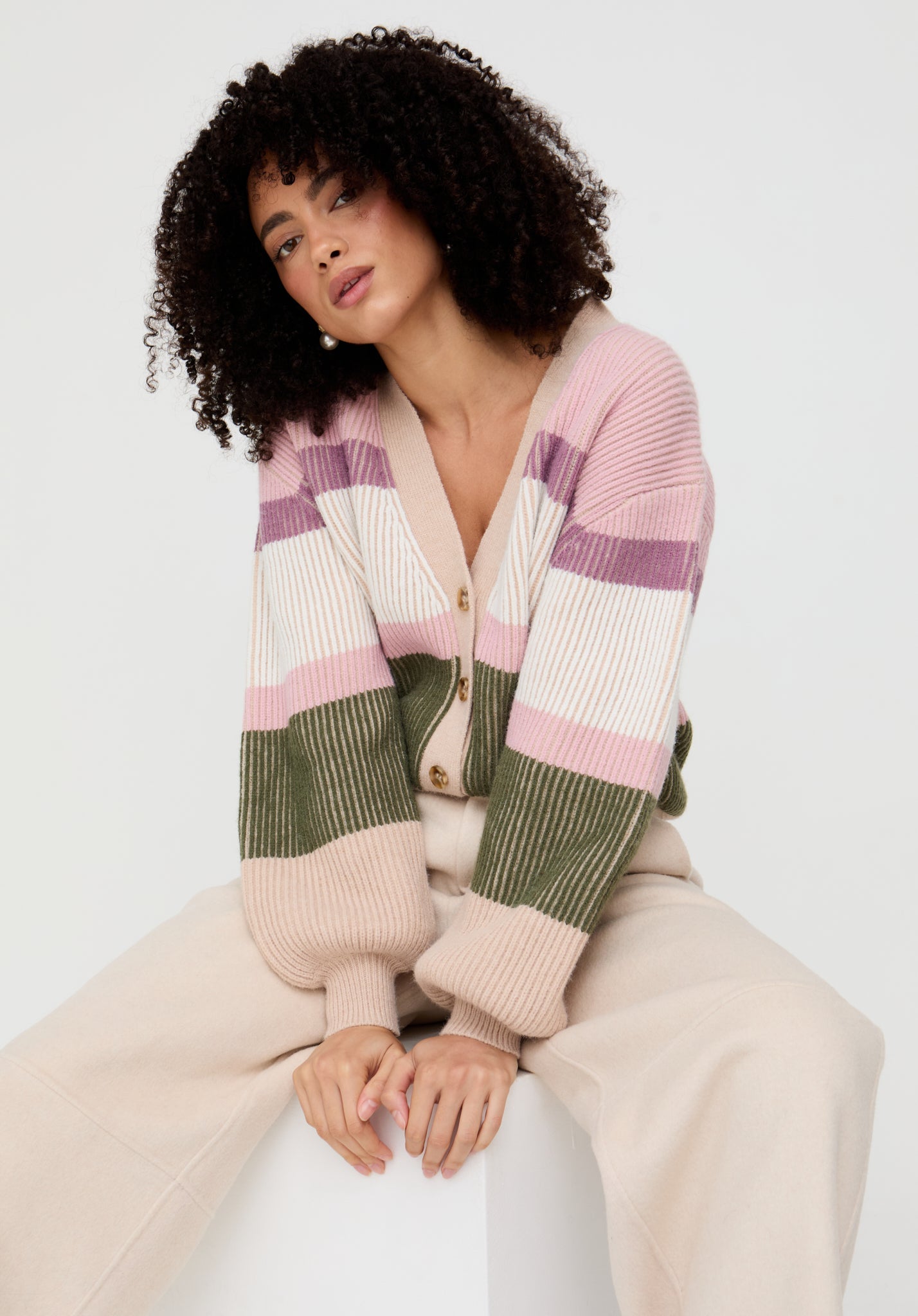 Woman wearing a striped cardigan with a neutral background