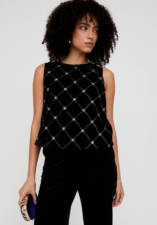 Woman wearing a black sleeveless top with a diamond pattern on a white background