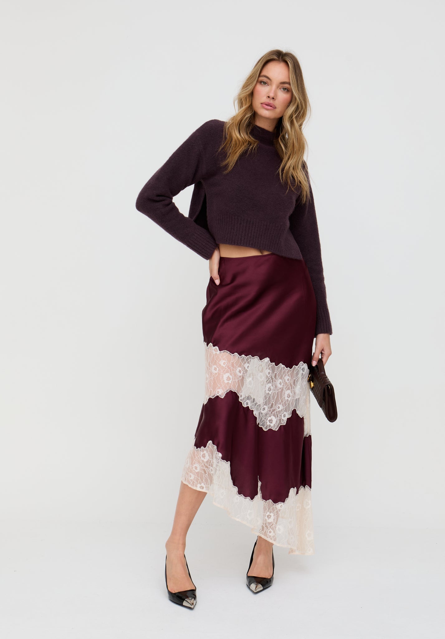 Woman wearing a burgundy top and skirt with lace details on a white background