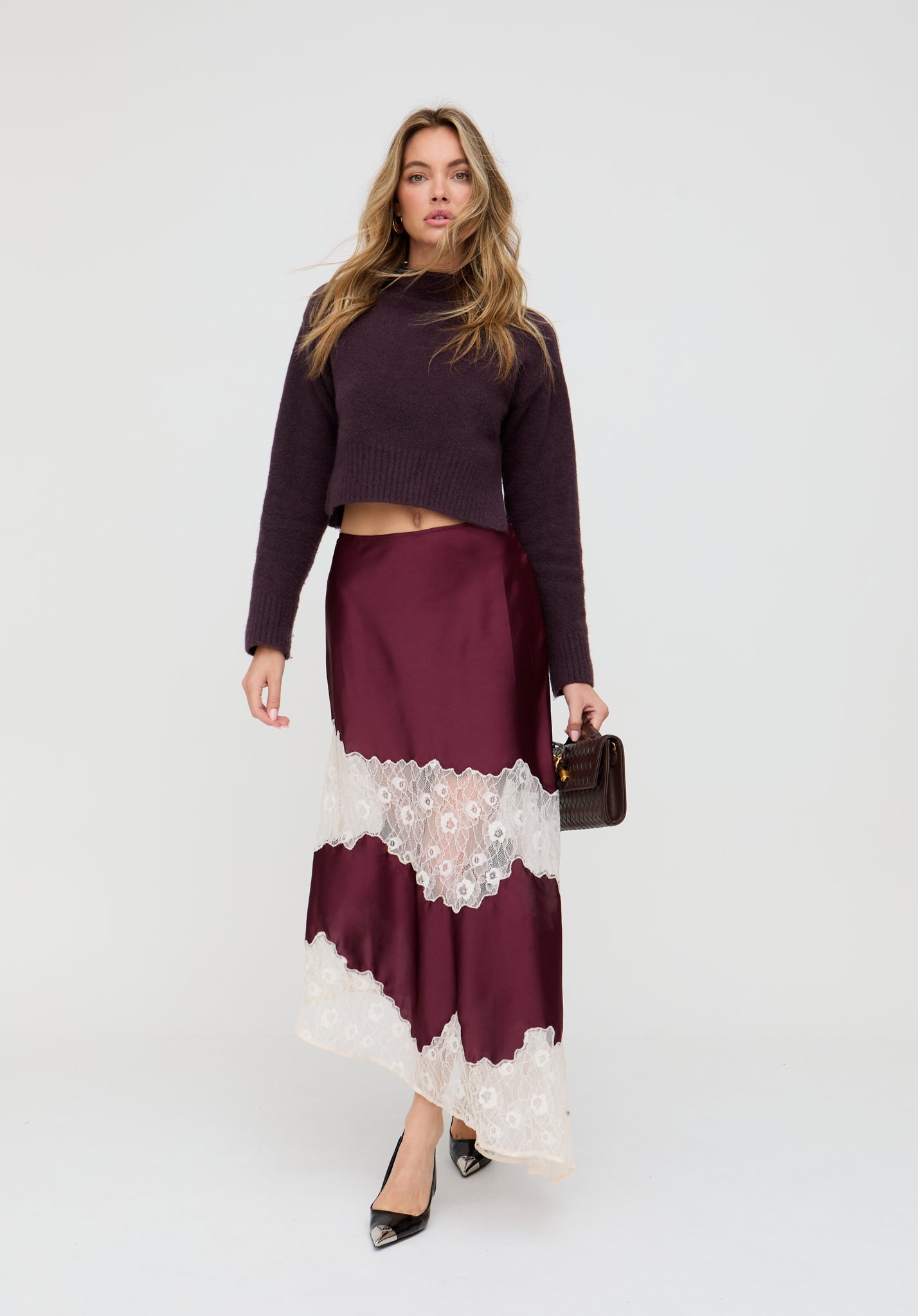 Woman wearing a burgundy top and skirt with lace details on a white background
