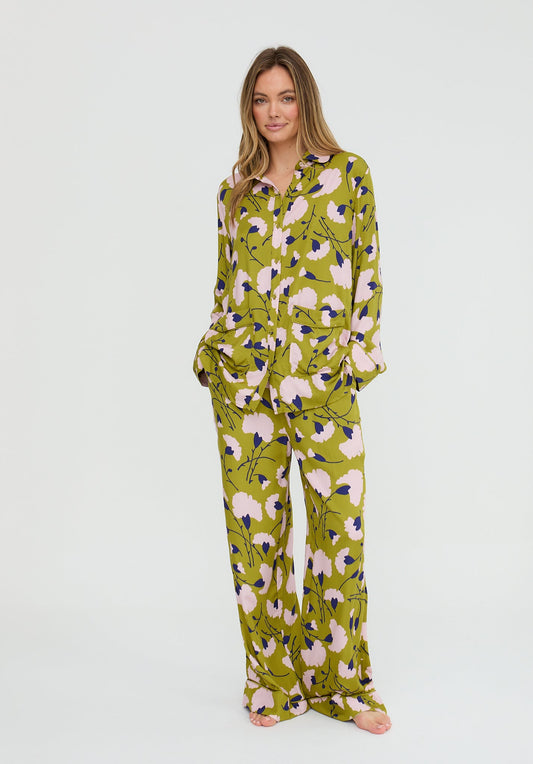 Woman wearing a green floral pajama set on a white background