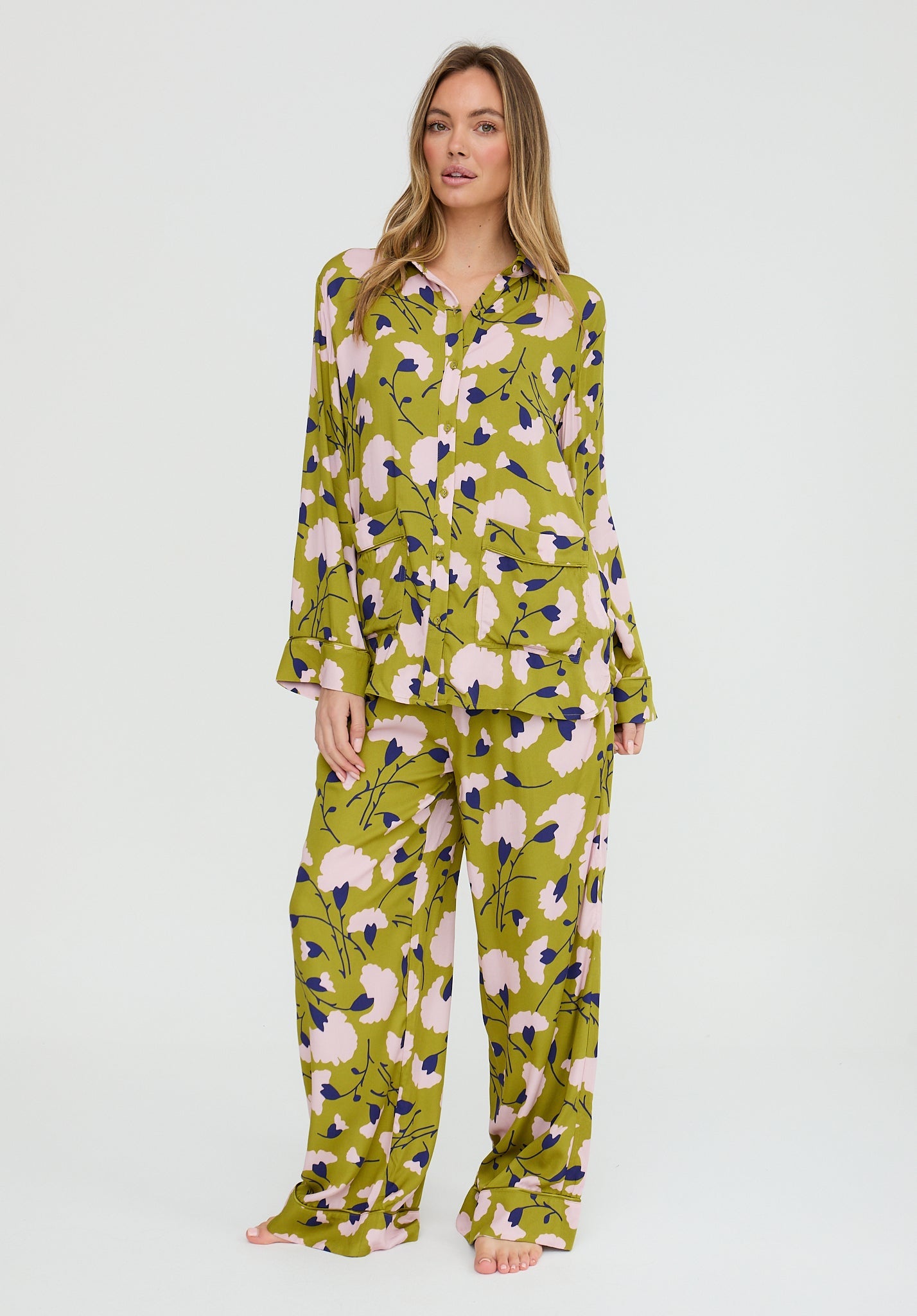 Woman wearing a green floral pajama set on a white background