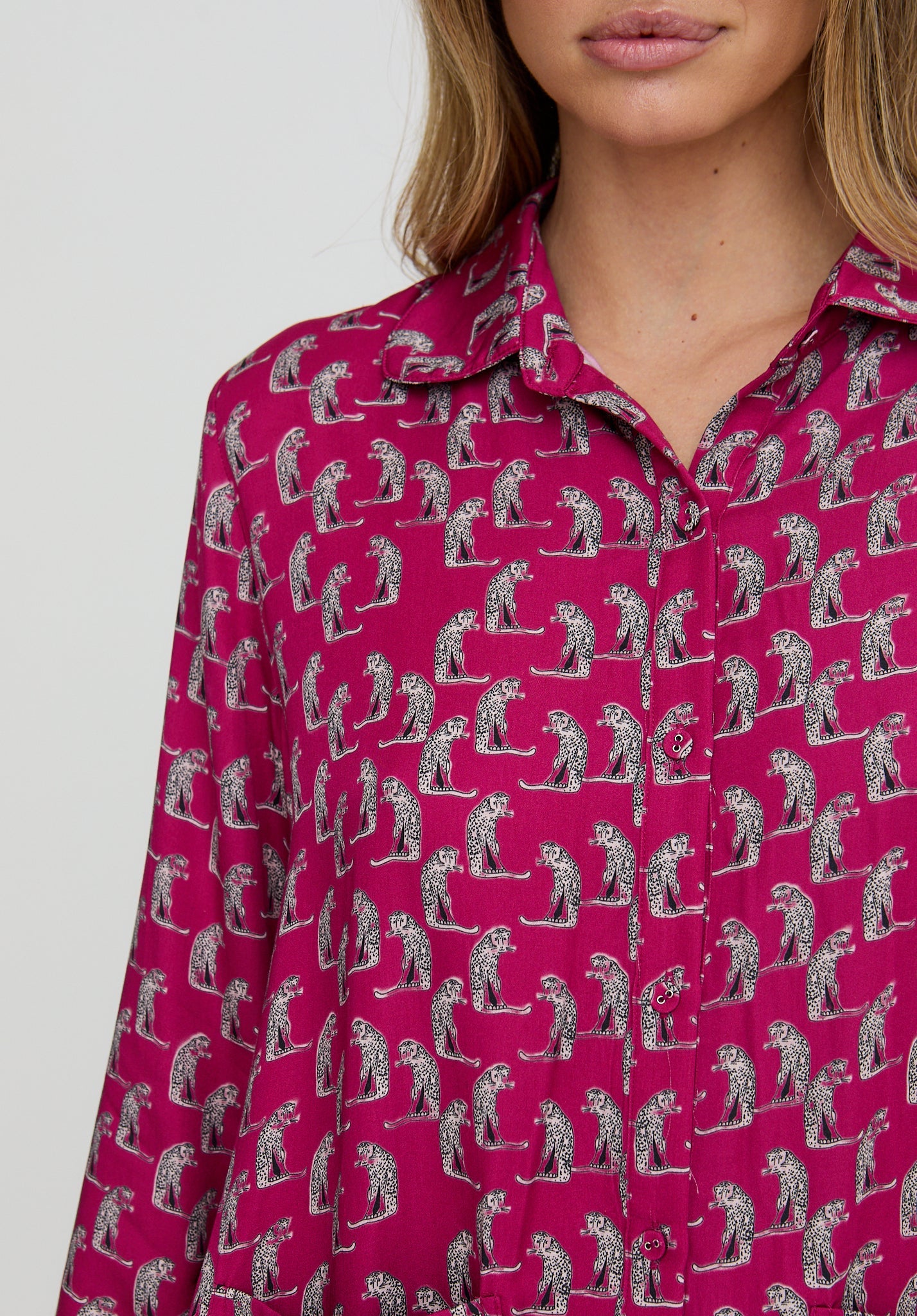 Person wearing a pink shirt with a pattern of people playing golf on a white background