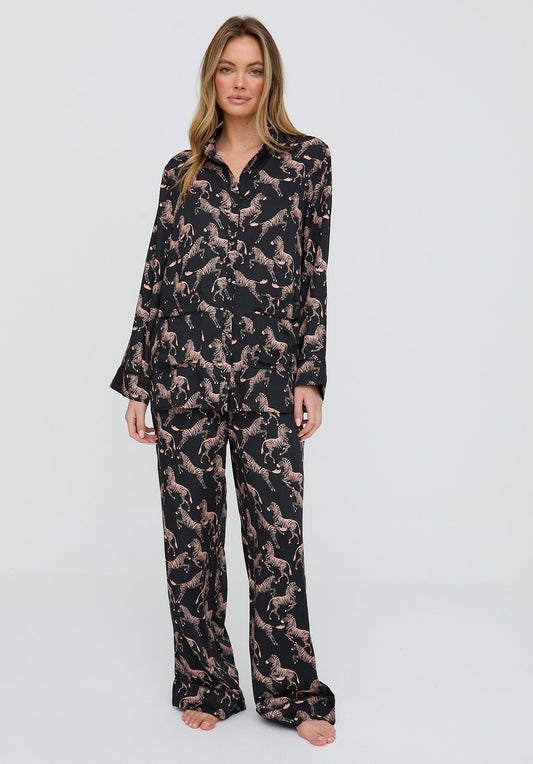 Woman wearing a black and pink patterned pajama set on a light gray background