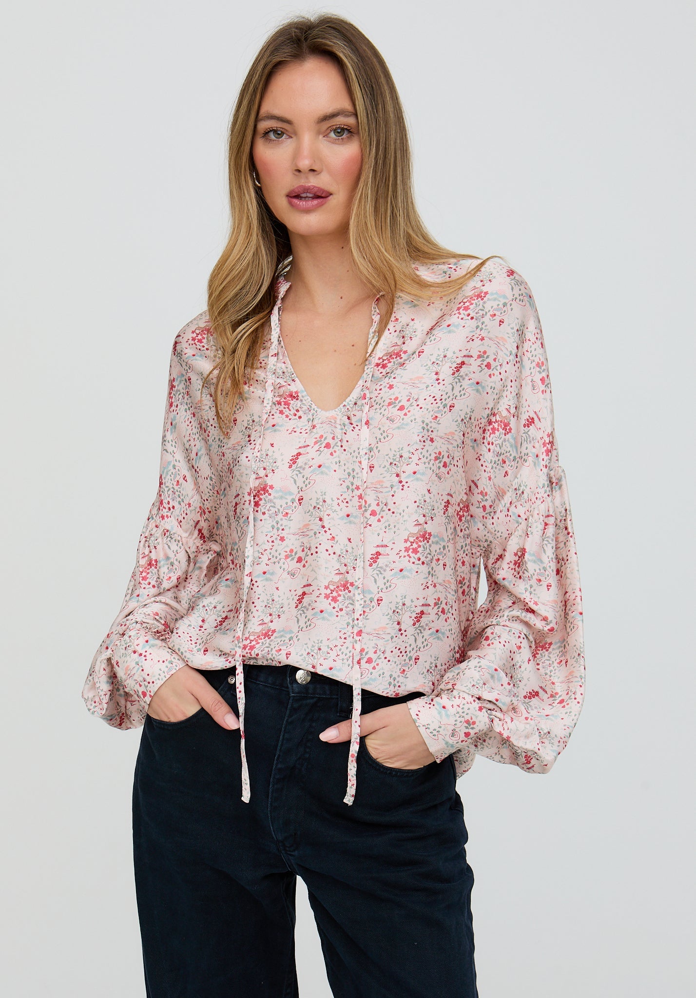 Woman wearing a floral blouse with long sleeves on a plain background
