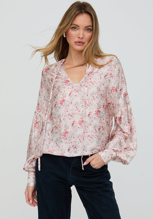 Woman wearing a floral blouse with long sleeves on a plain background