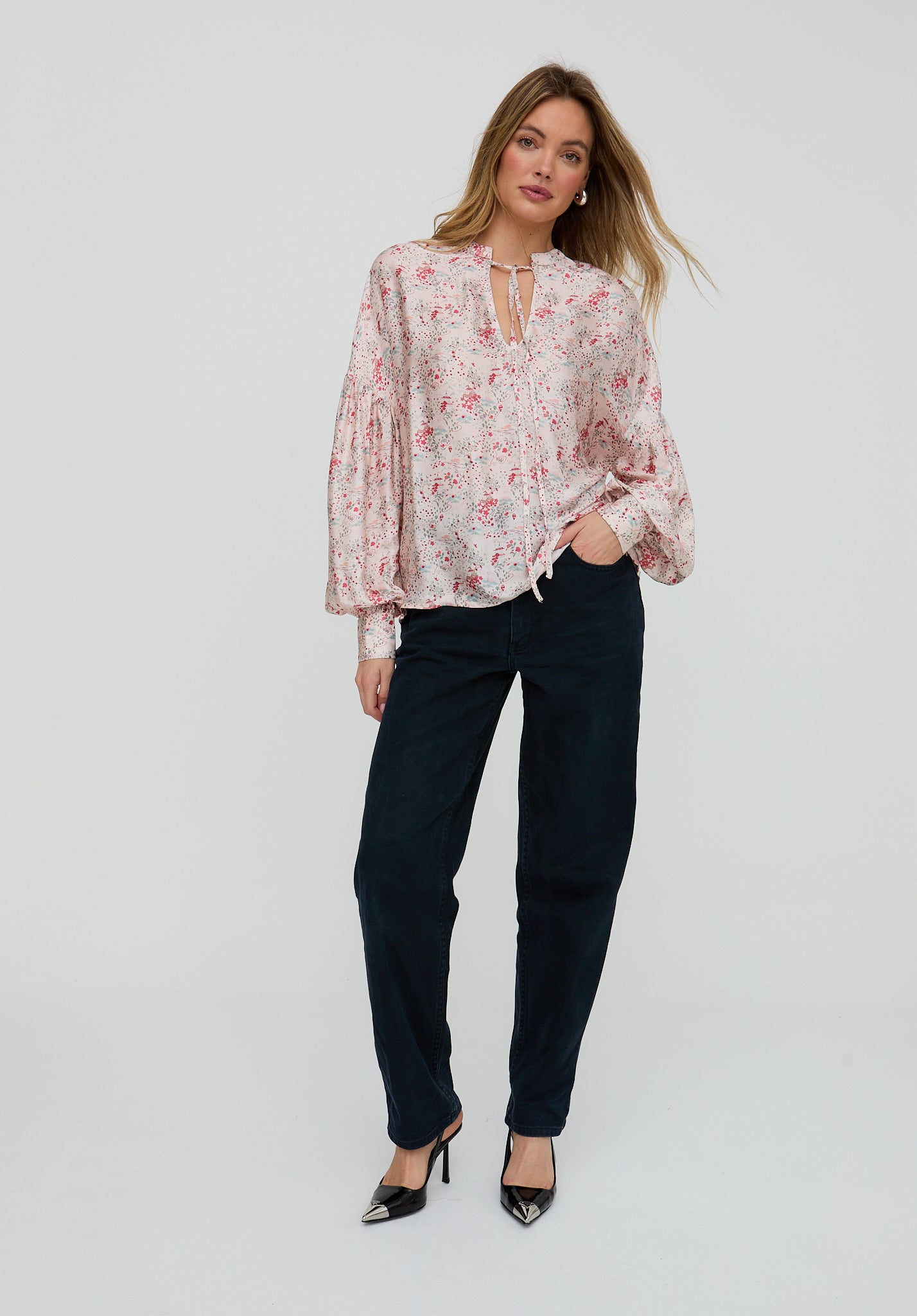 Woman wearing a floral blouse and black pants on a white background