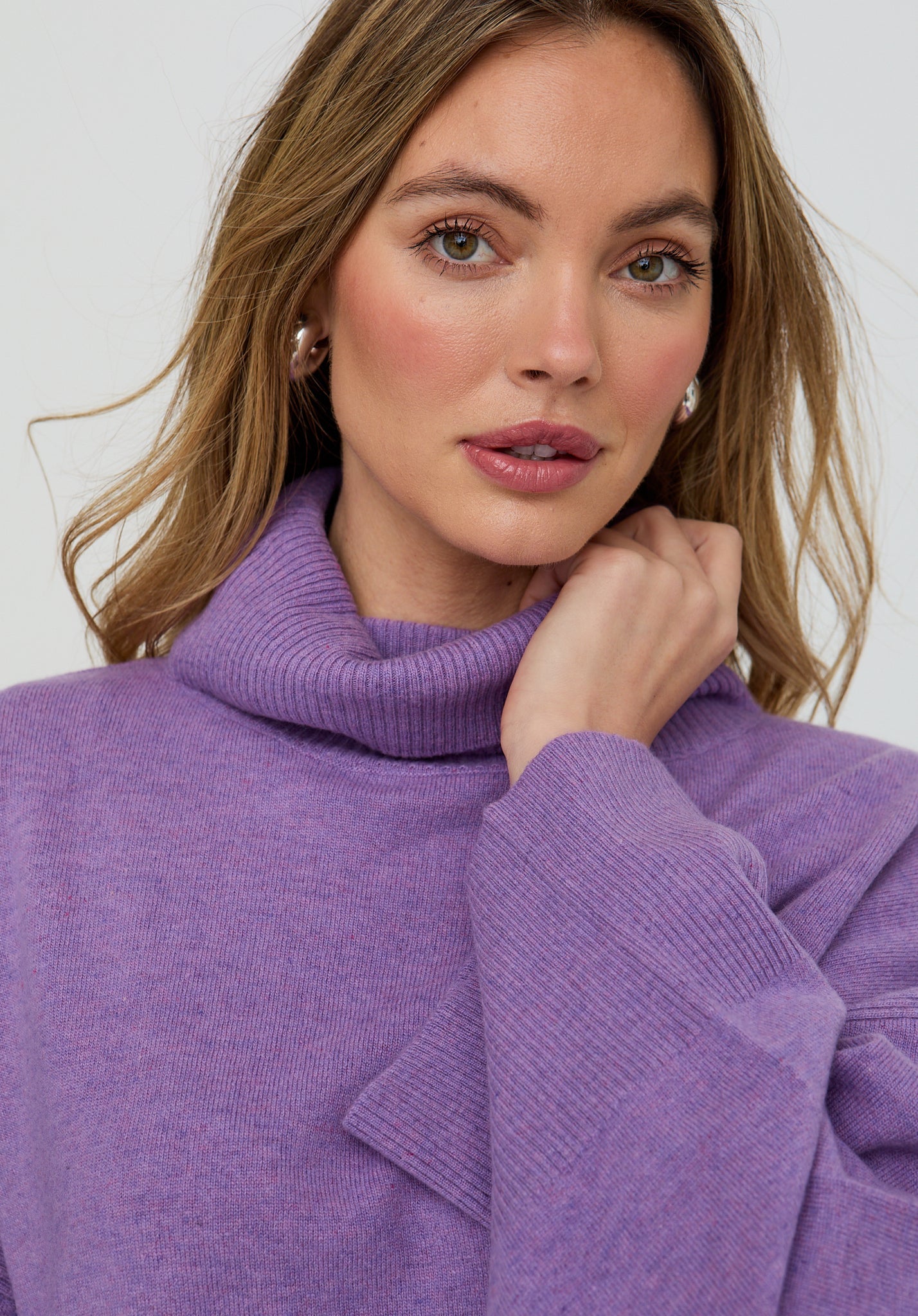 Woman wearing a purple turtleneck sweater against a white background