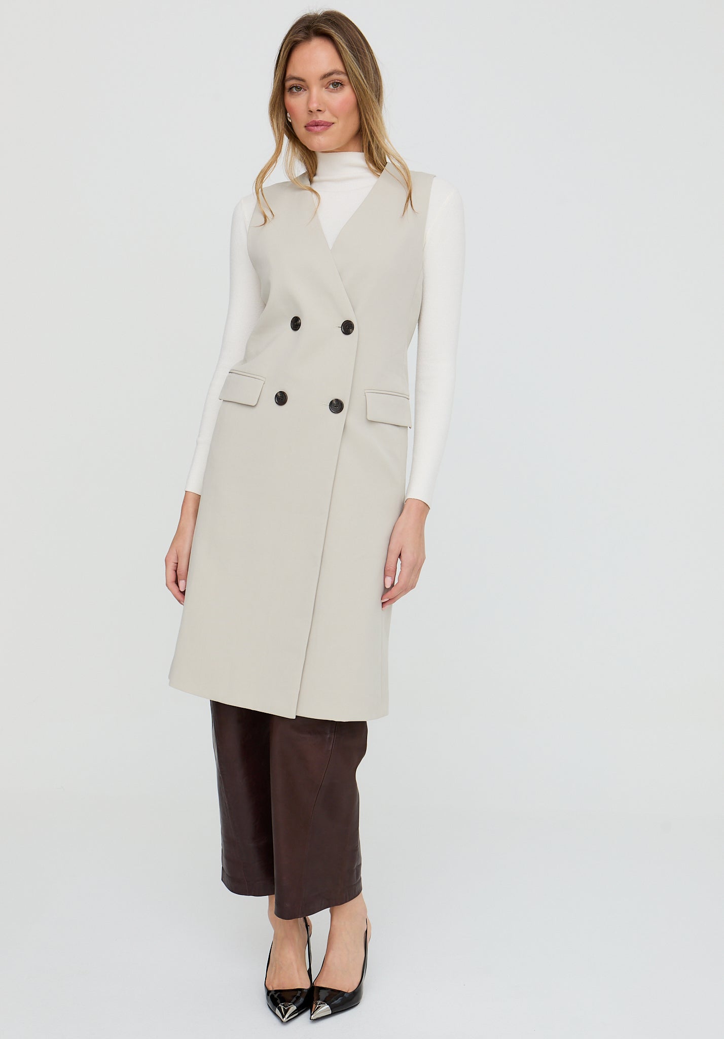 Woman wearing a beige long coat with black buttons on a white background