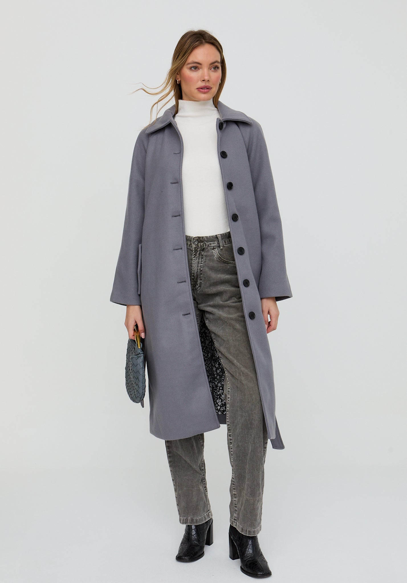 Woman wearing a long gray coat on a white background