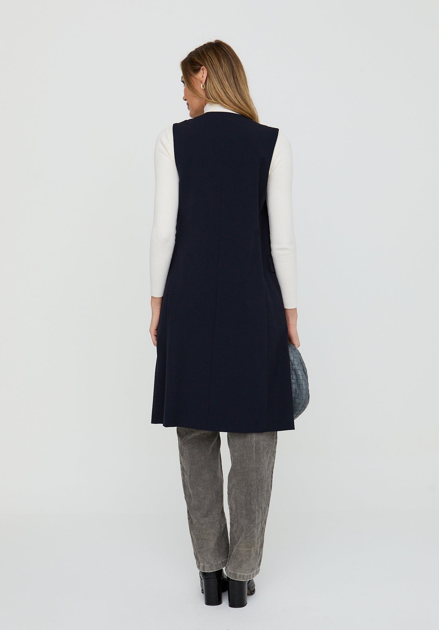 Woman wearing a navy vest over a white shirt on a white background