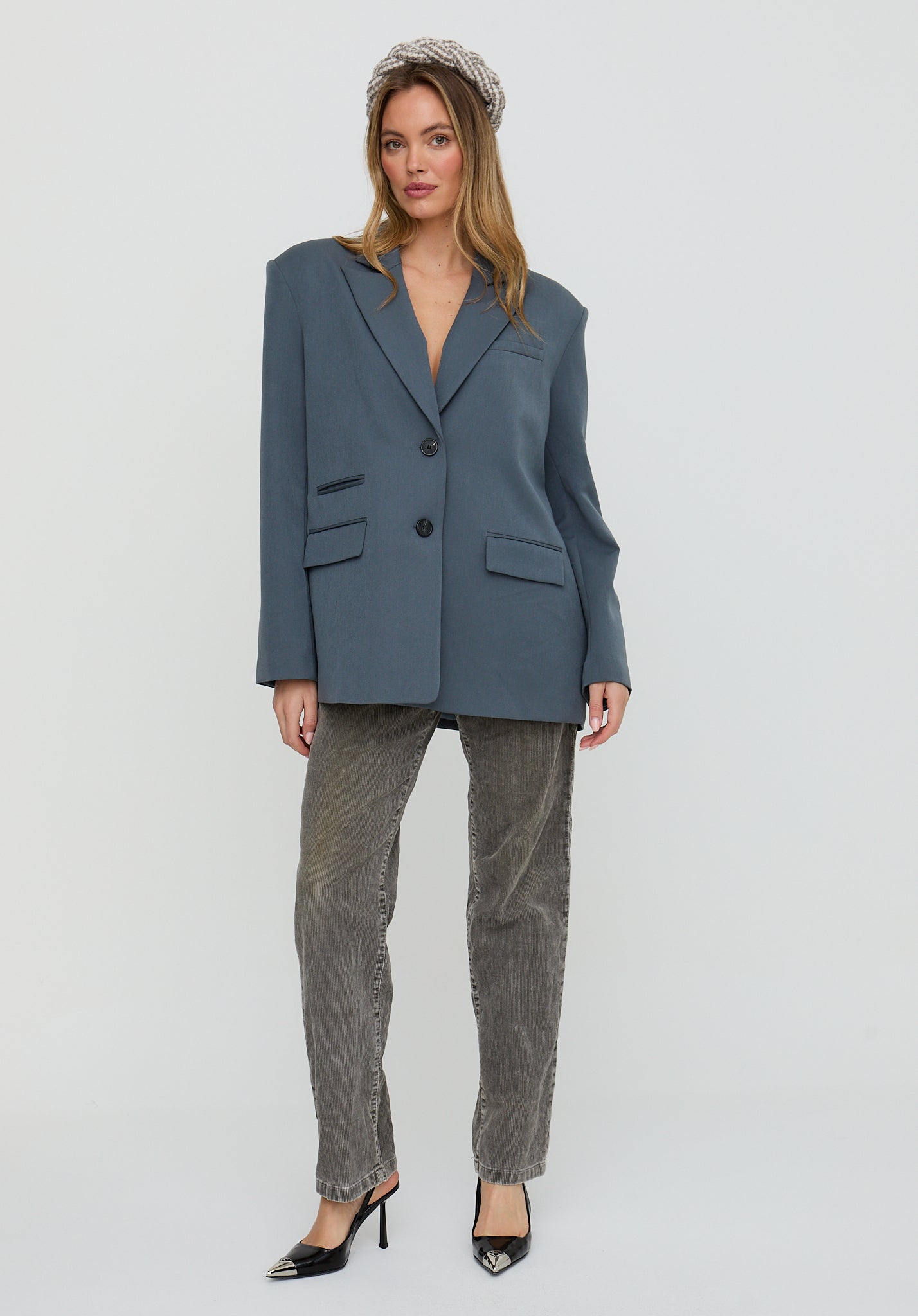 Woman wearing a blue blazer and gray pants on a white background