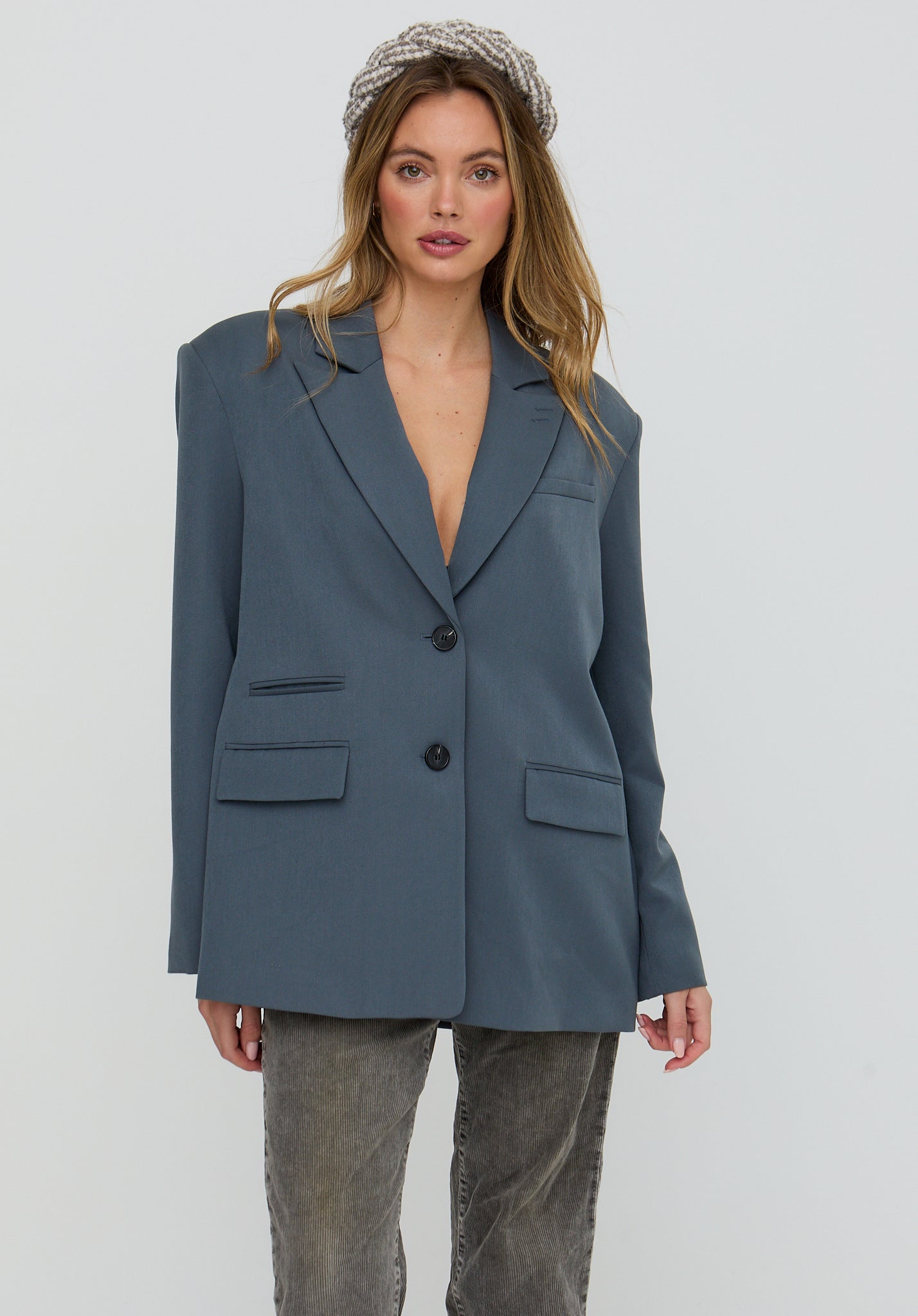 Woman wearing a blue blazer and gray pants on a white background