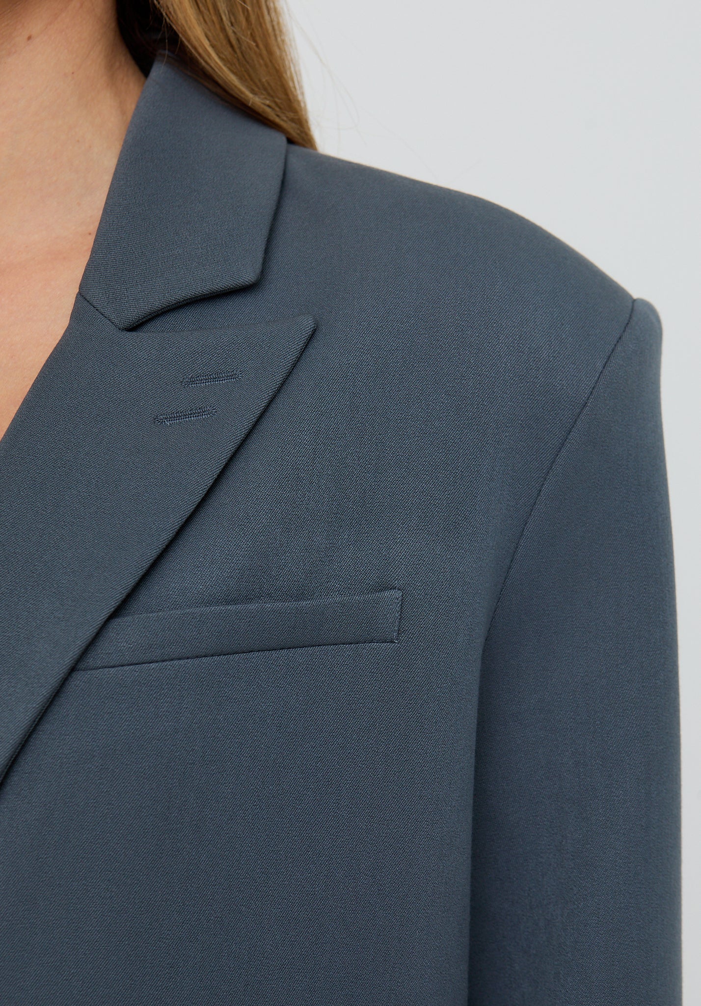 Close-up of a gray blazer with a pocket on a plain background