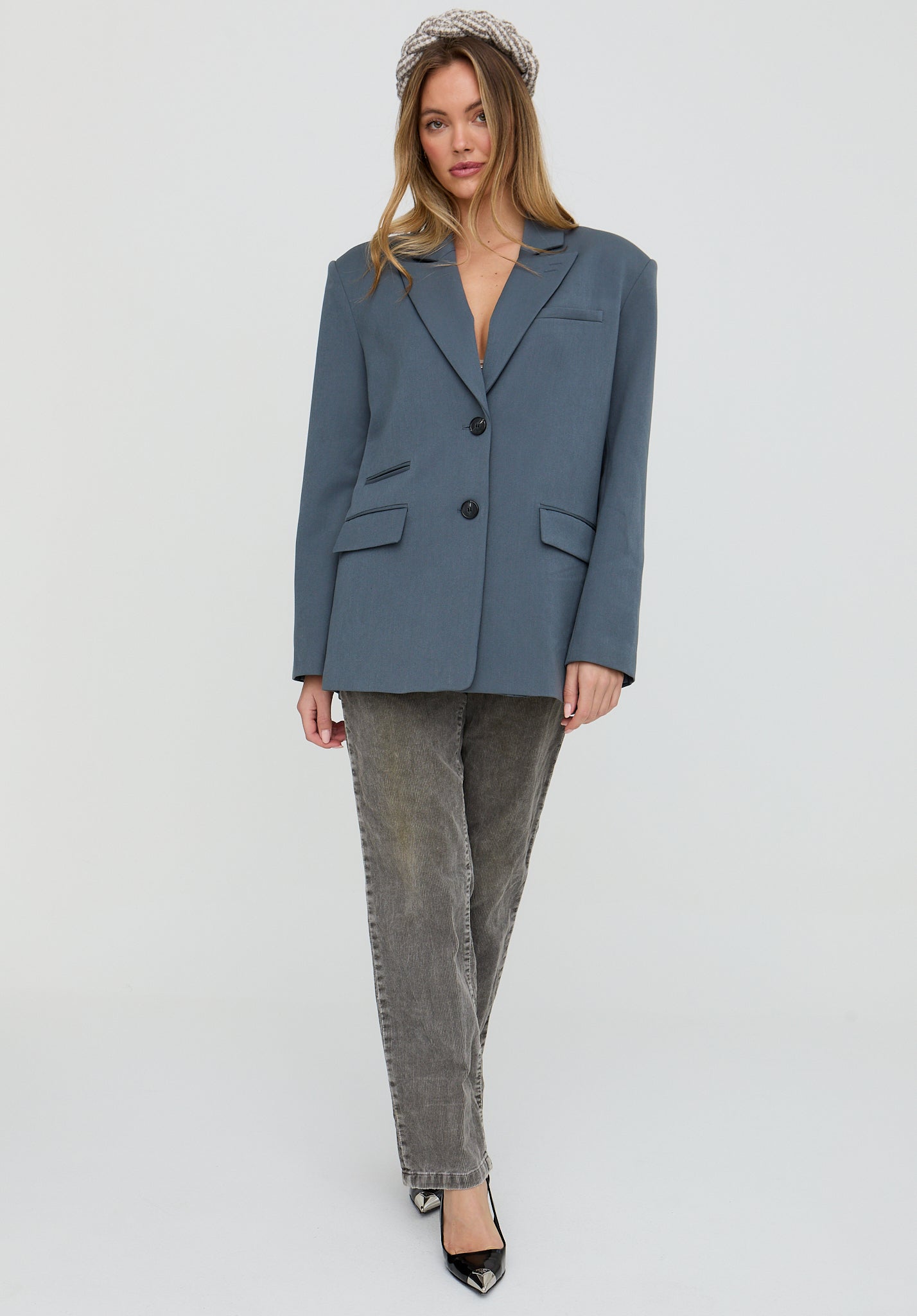 Woman wearing a blue blazer and gray pants on a white background