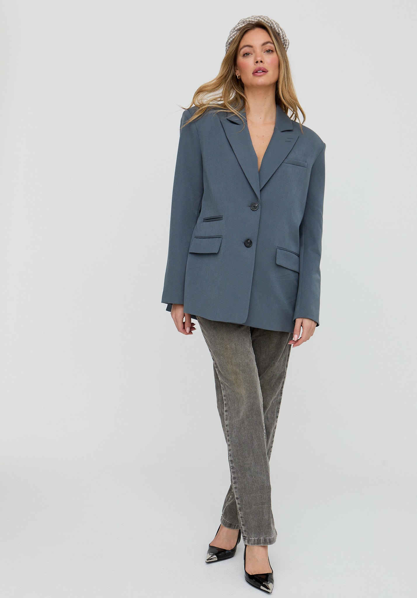 Woman wearing a blue blazer and gray pants on a white background