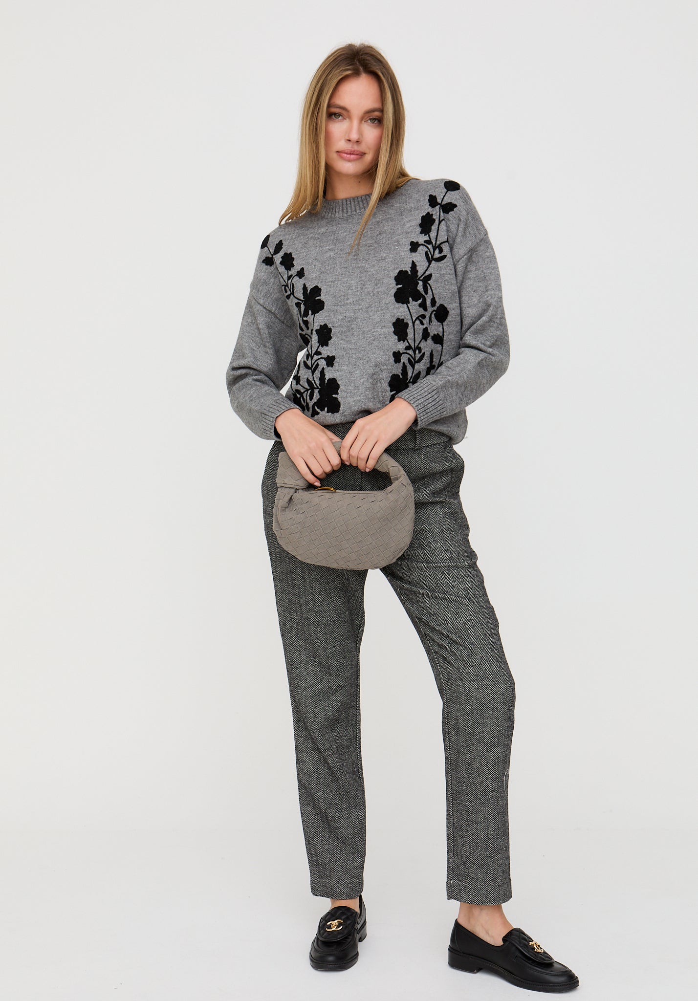 Woman wearing a gray sweater with black floral patterns and matching pants on a white background