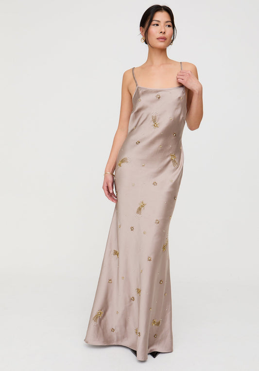 Woman wearing a beige satin dress with gold embroidery on a white background