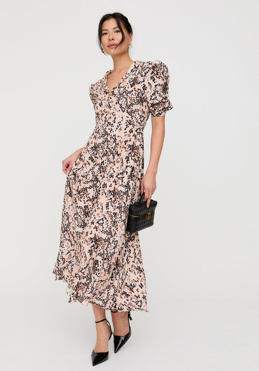 Woman wearing a floral dress holding a clutch against a white background