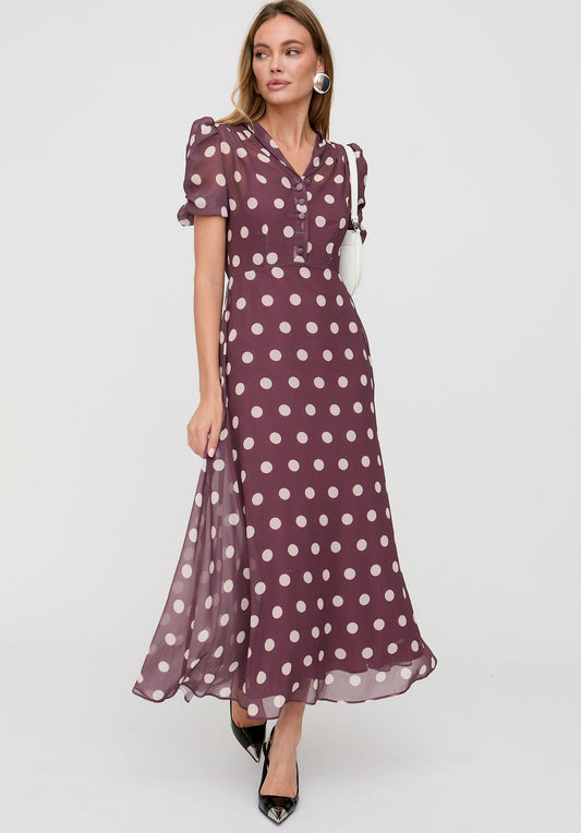 Woman wearing a purple polka dot dress on a white background