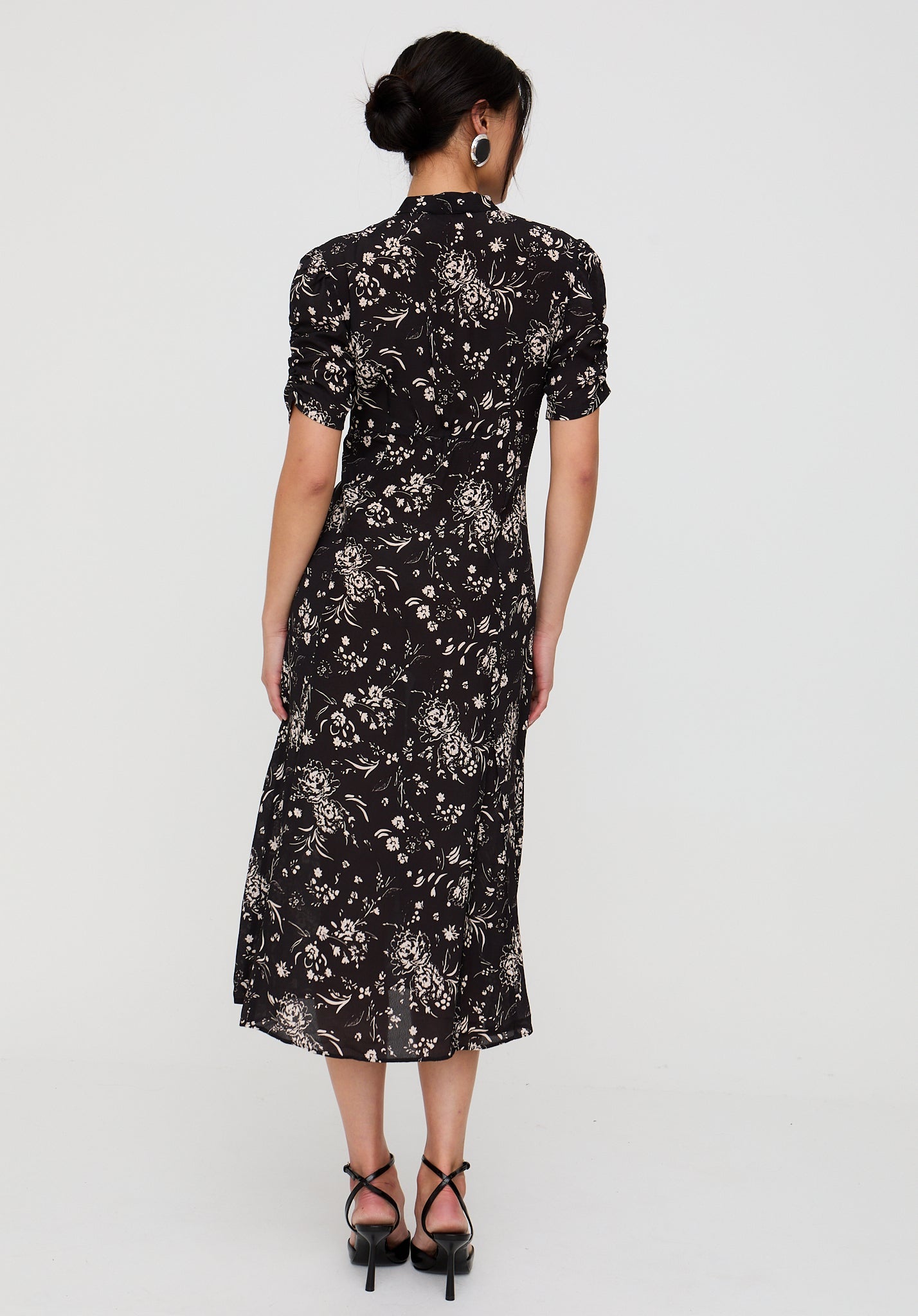 Woman wearing a black floral dress against a white background