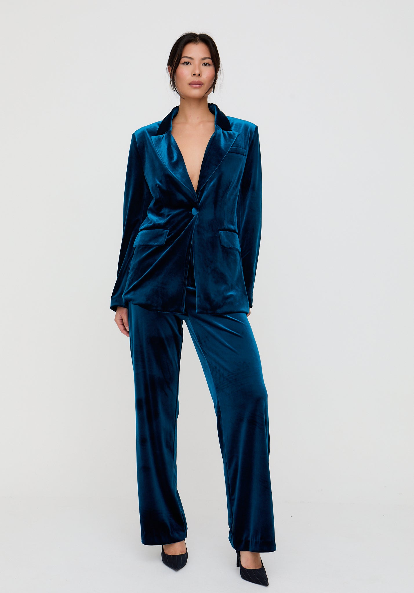 Woman wearing a teal satin suit on a white background