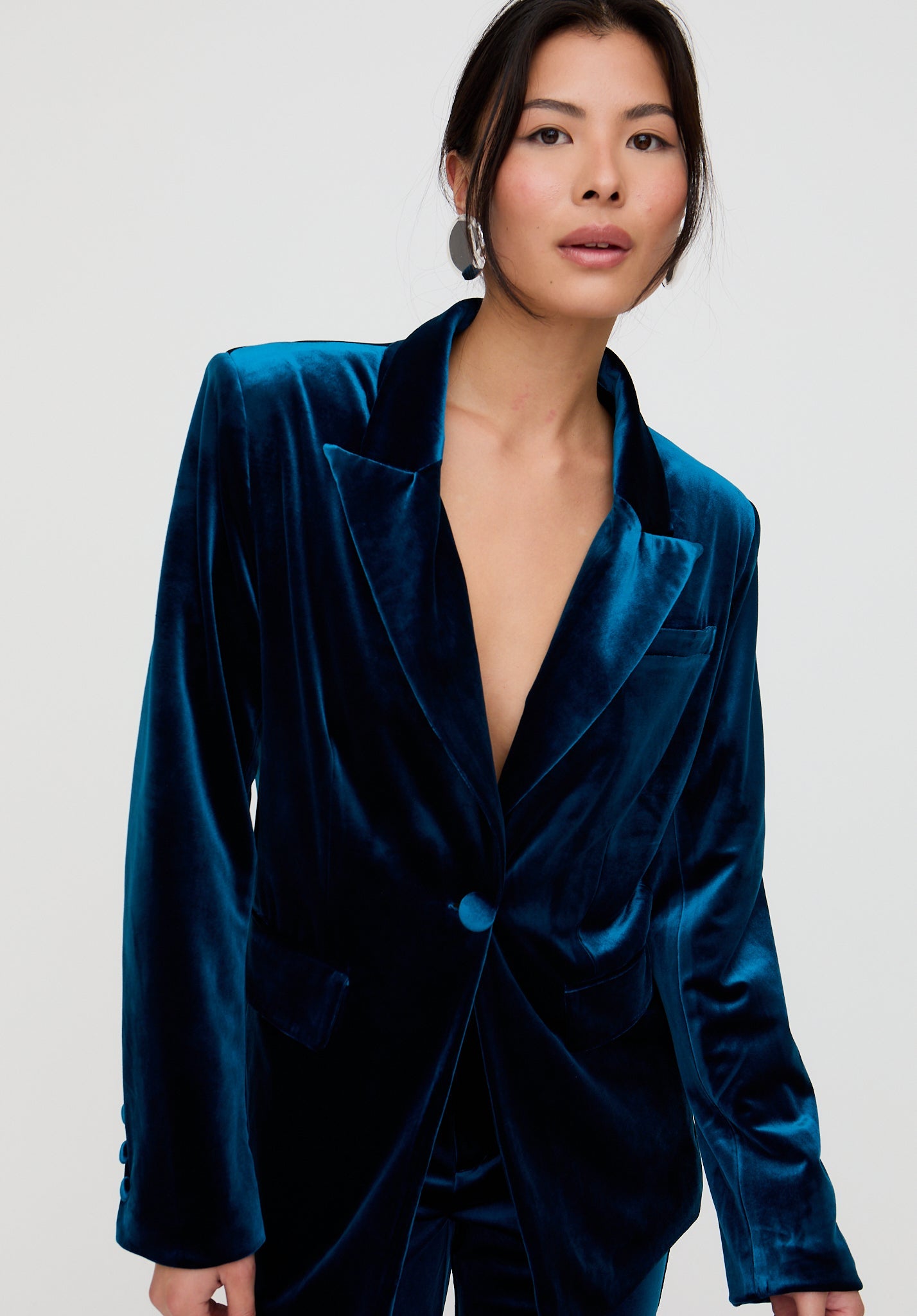 Woman wearing a blue velvet blazer against a white background