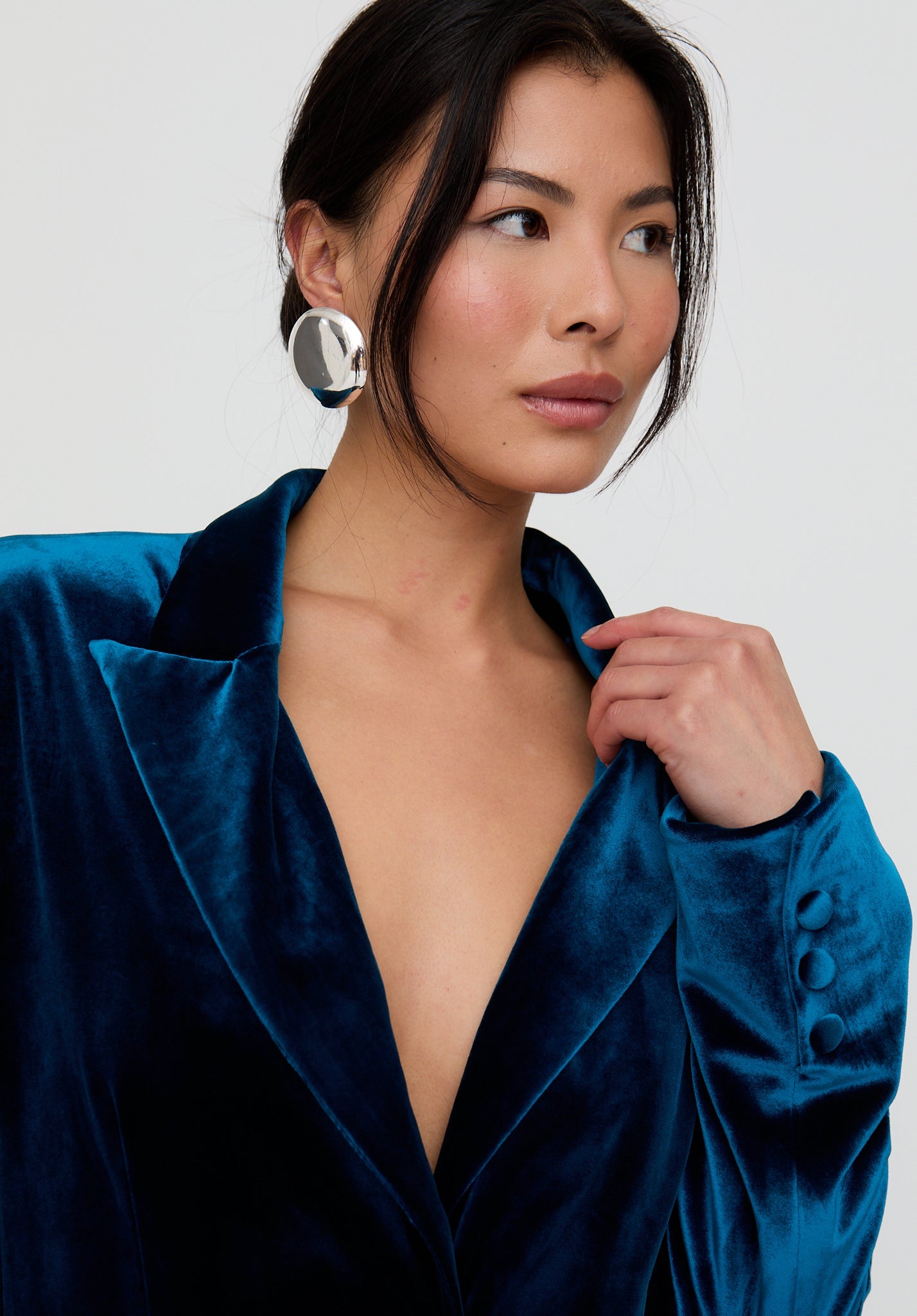Woman wearing a blue velvet garment with a plain background