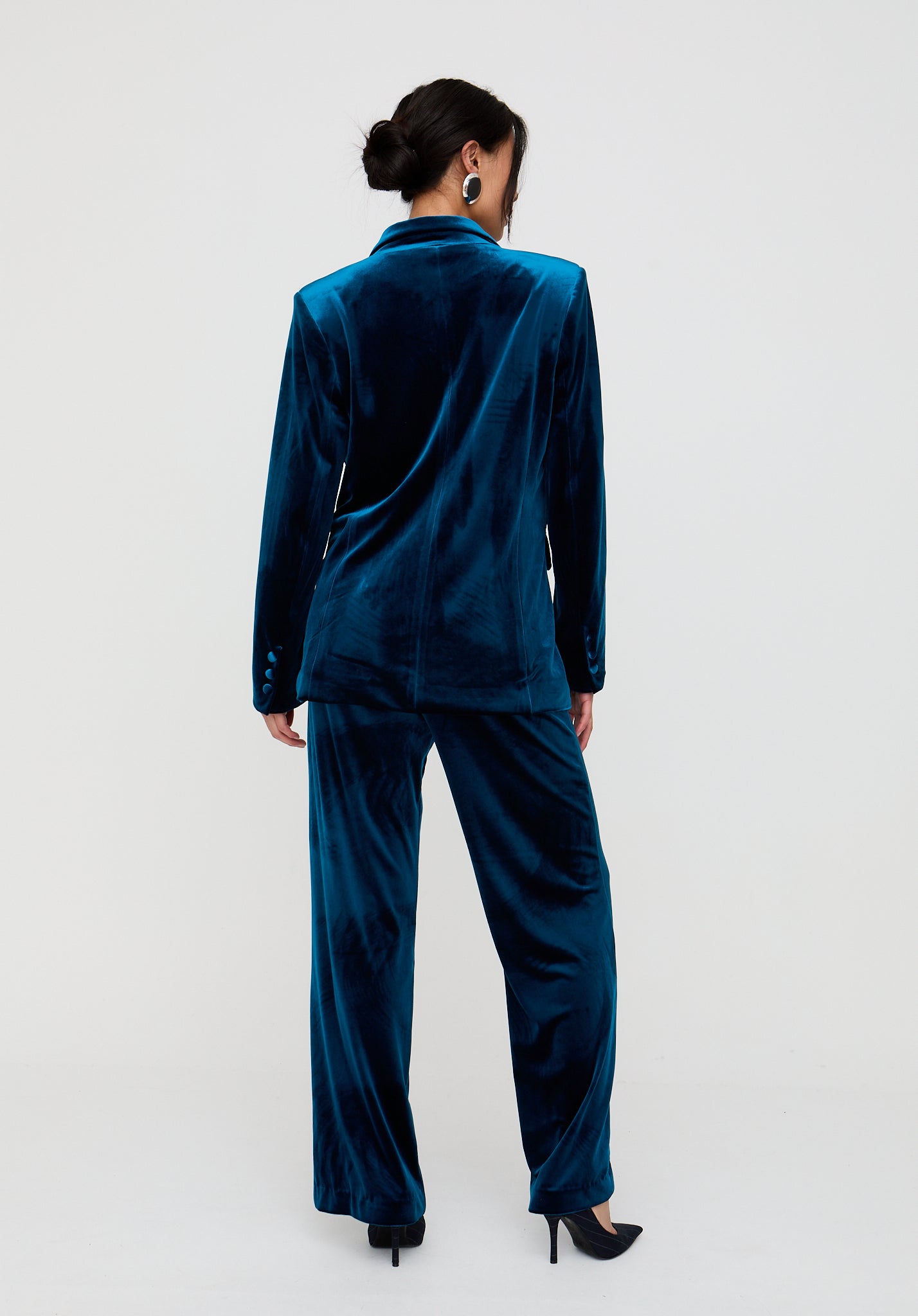 Woman wearing a teal velvet suit on a white background