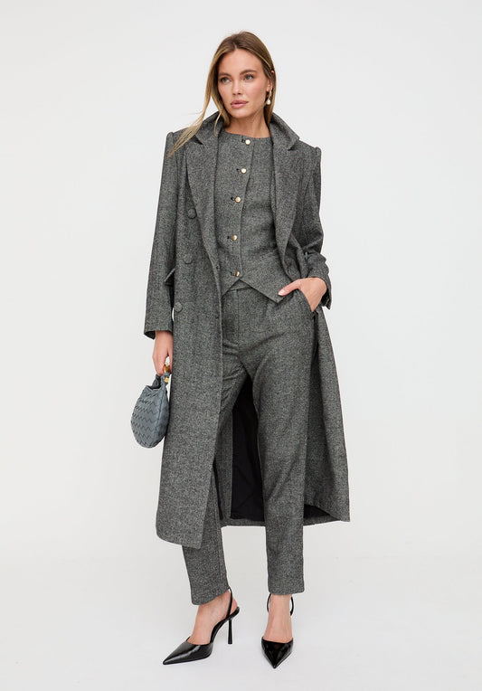 Woman wearing a gray suit with a long coat on a white background