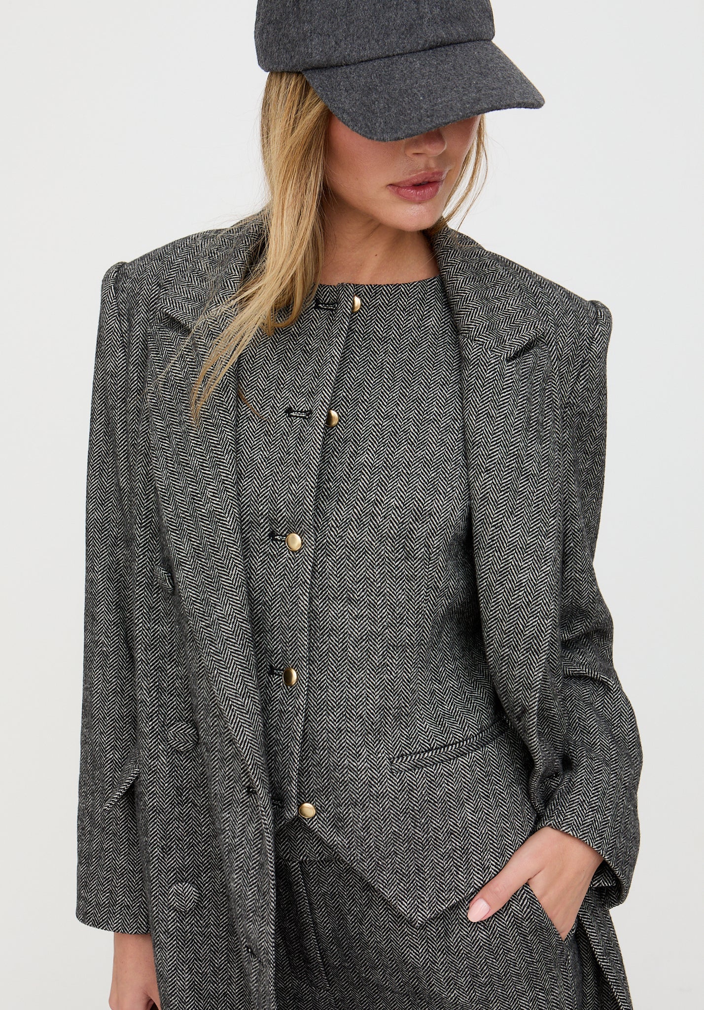 Person wearing a gray textured suit with a matching cap on a white background