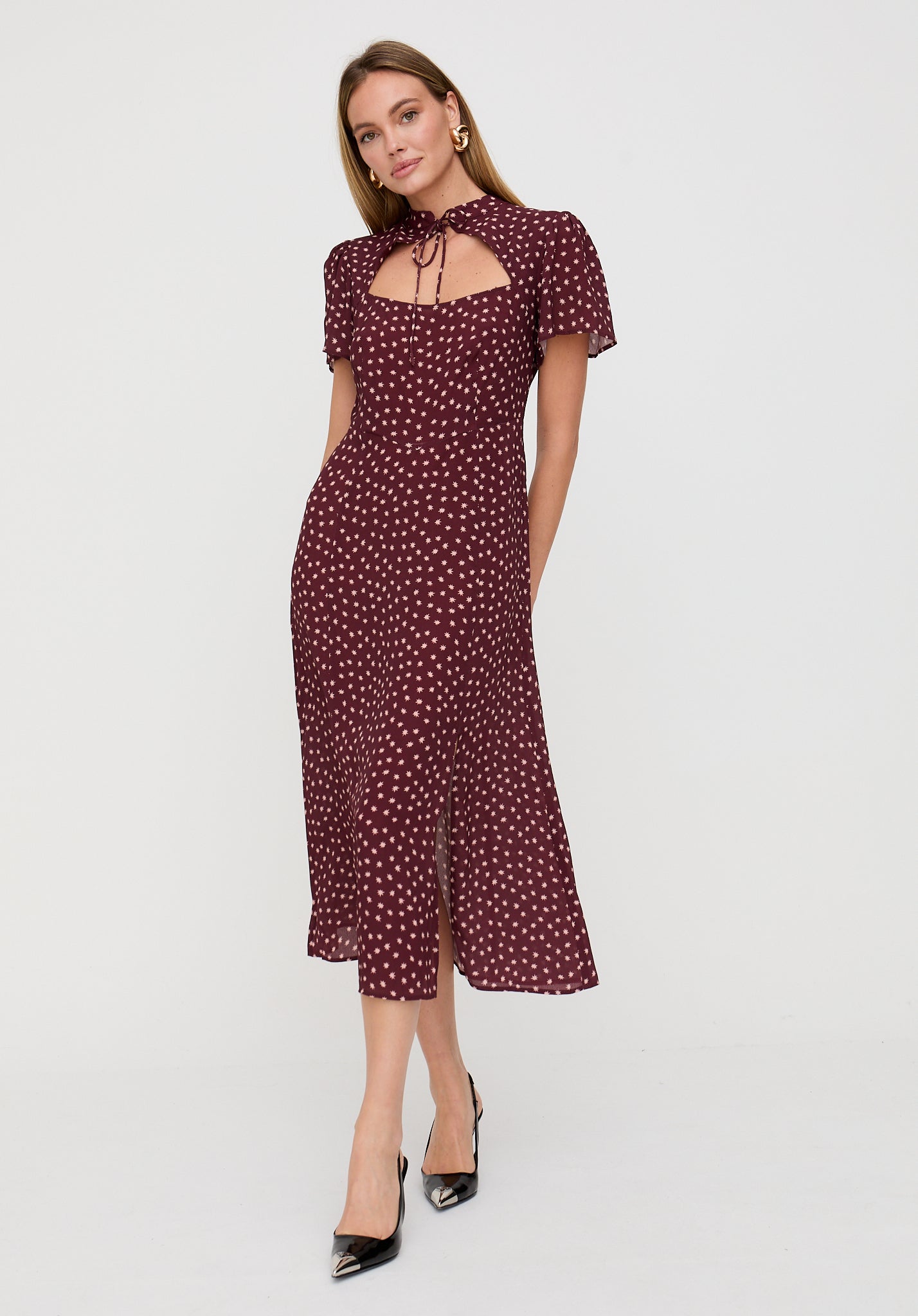 Woman wearing a burgundy dress with white polka dots on a white background