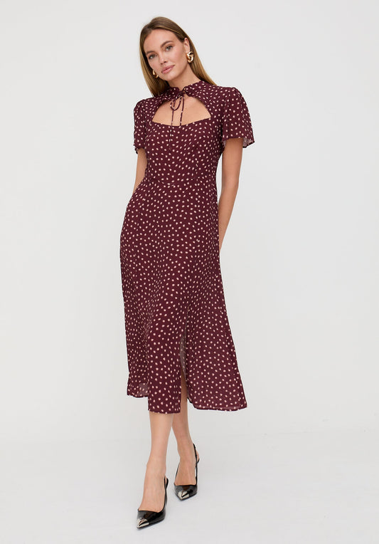 Woman wearing a burgundy dress with white polka dots on a white background