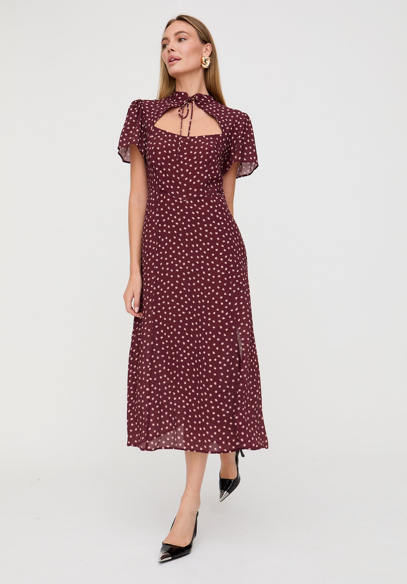 Woman wearing a burgundy dress with white polka dots on a white background