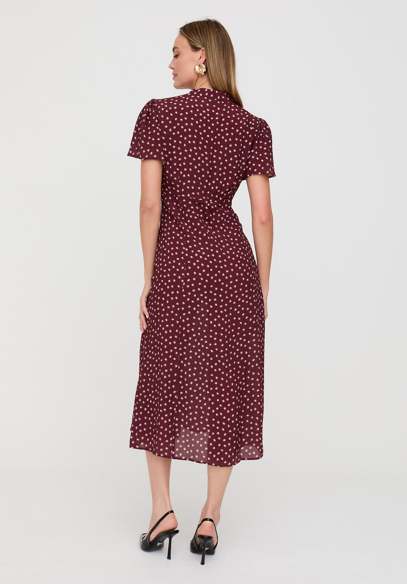 Woman wearing a burgundy dress with white polka dots on a white background