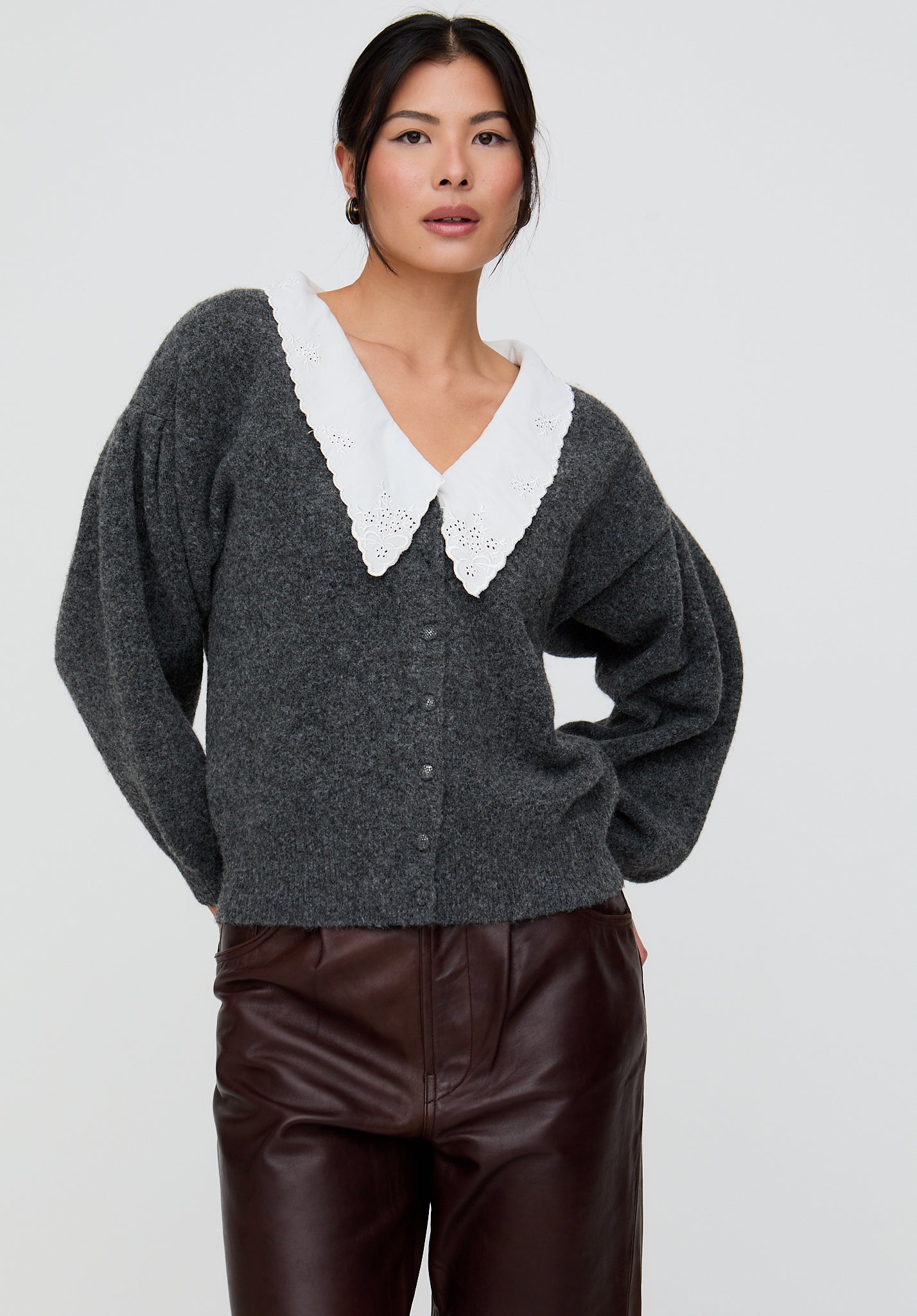 Woman wearing a dark gray cardigan with a white collar on a light gray background