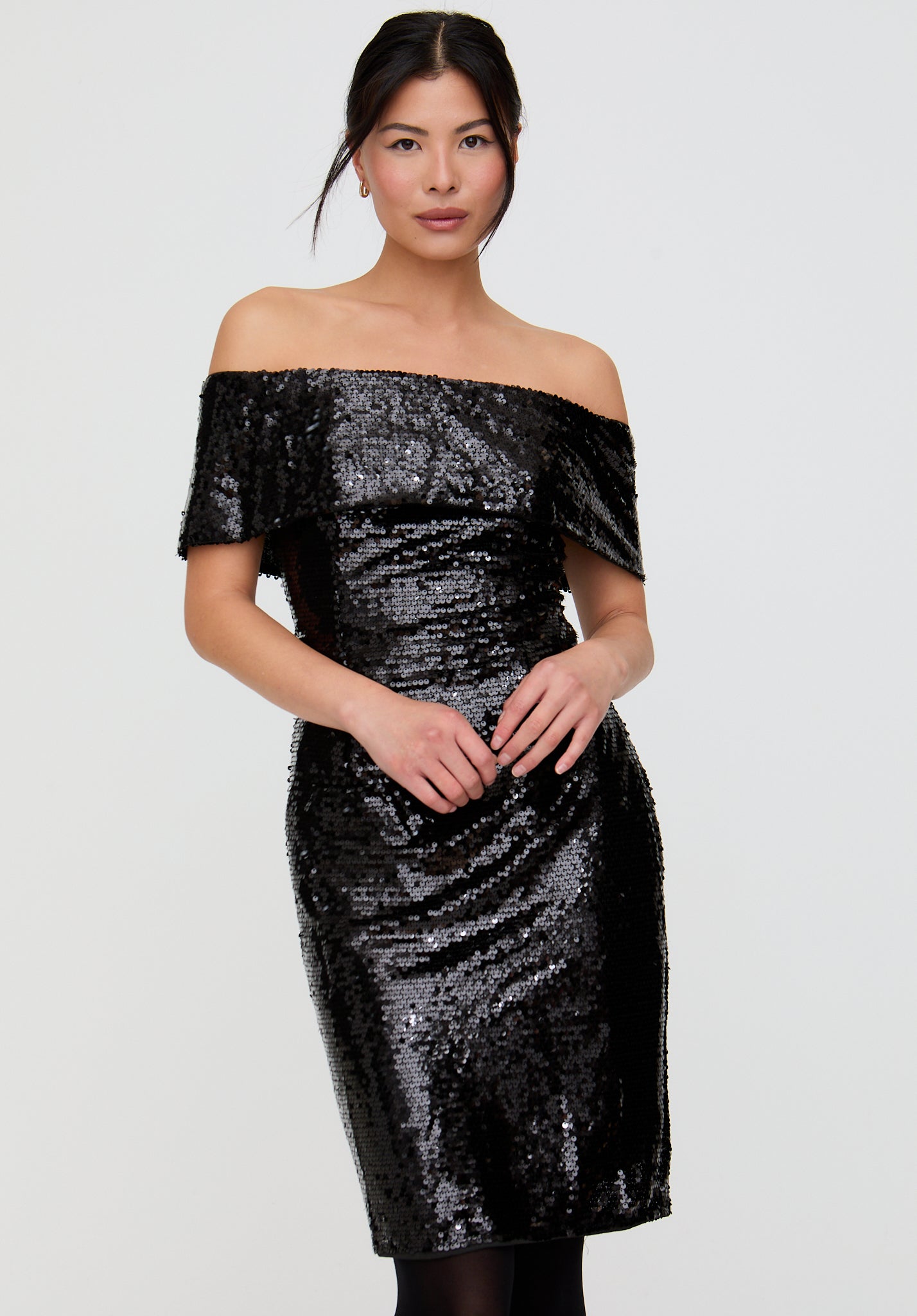 Woman wearing a black sequin off-shoulder dress on a white background